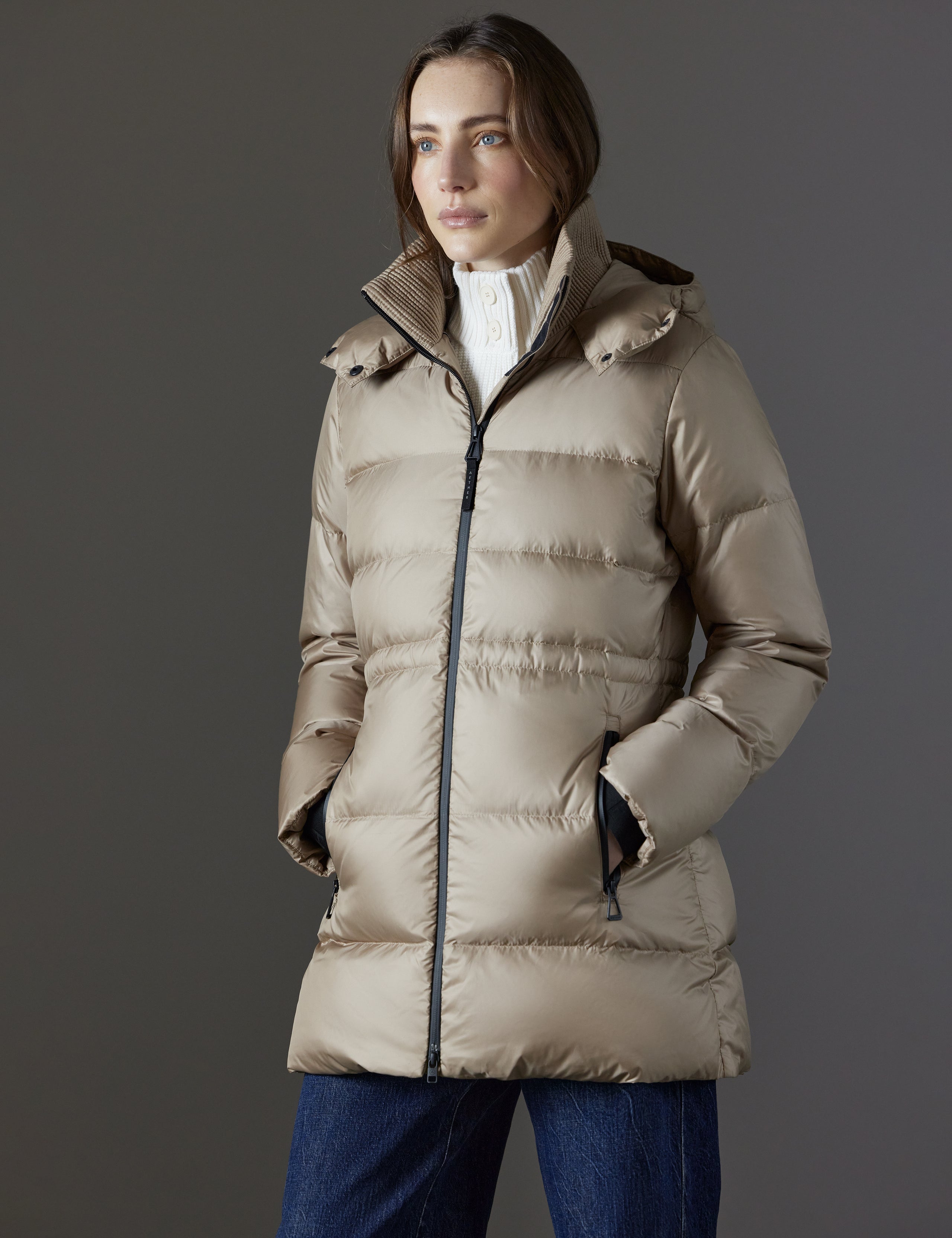 Front angled view of woman with hands in pockets wearing Aura Puffer Long in Chinchilla Brown from AETHER Apparel.