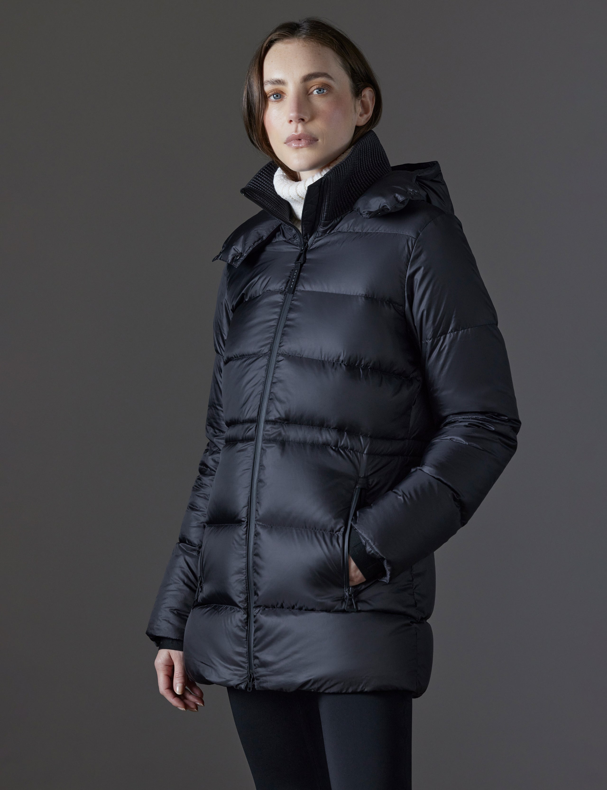 Front angled view of woman wearing Aura Puffer Long in Onyx Black from AETHER Apparel.