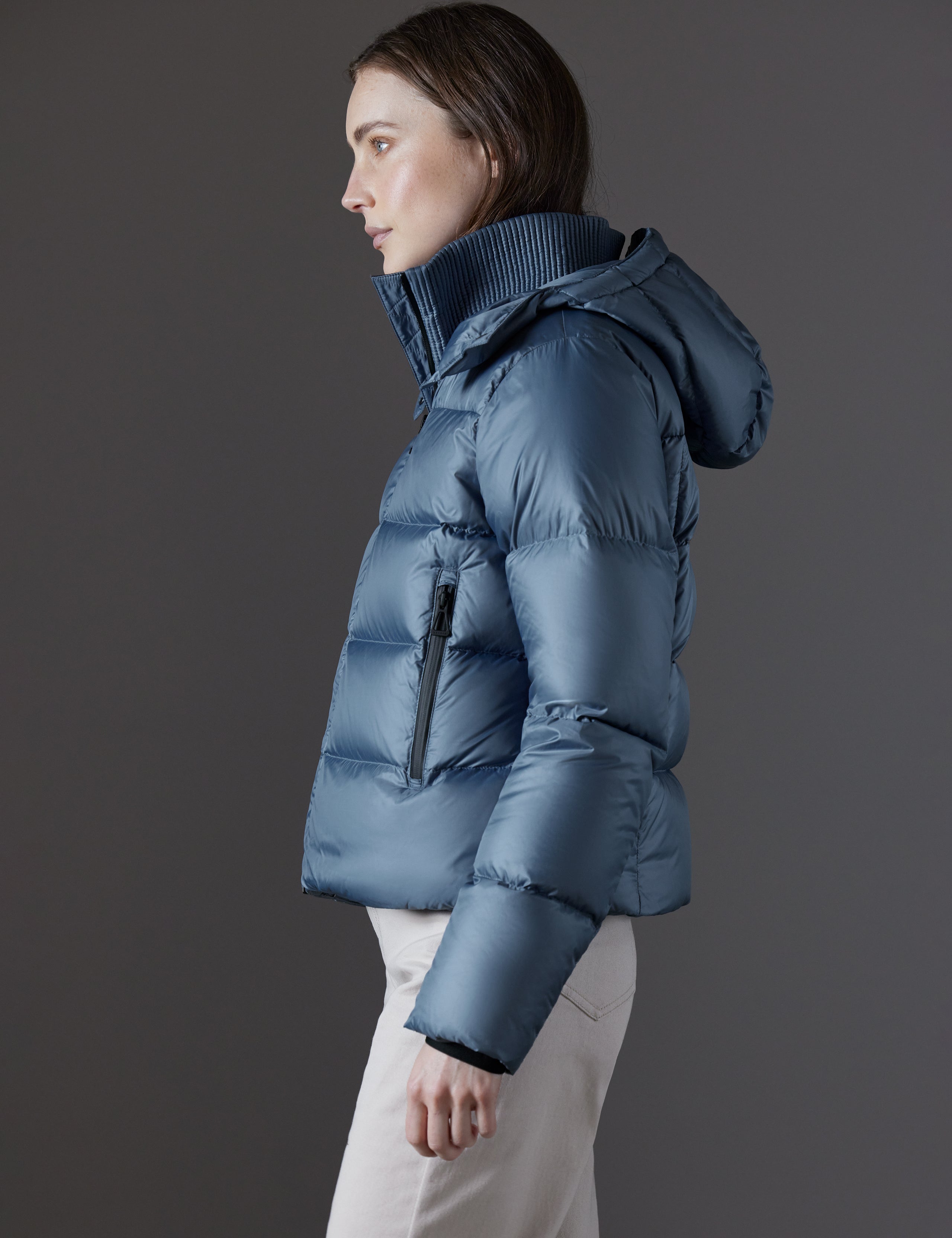 Side profile view of woman wearing Aura Puffer Jacket in Portal Blue from AETHER Apparel.