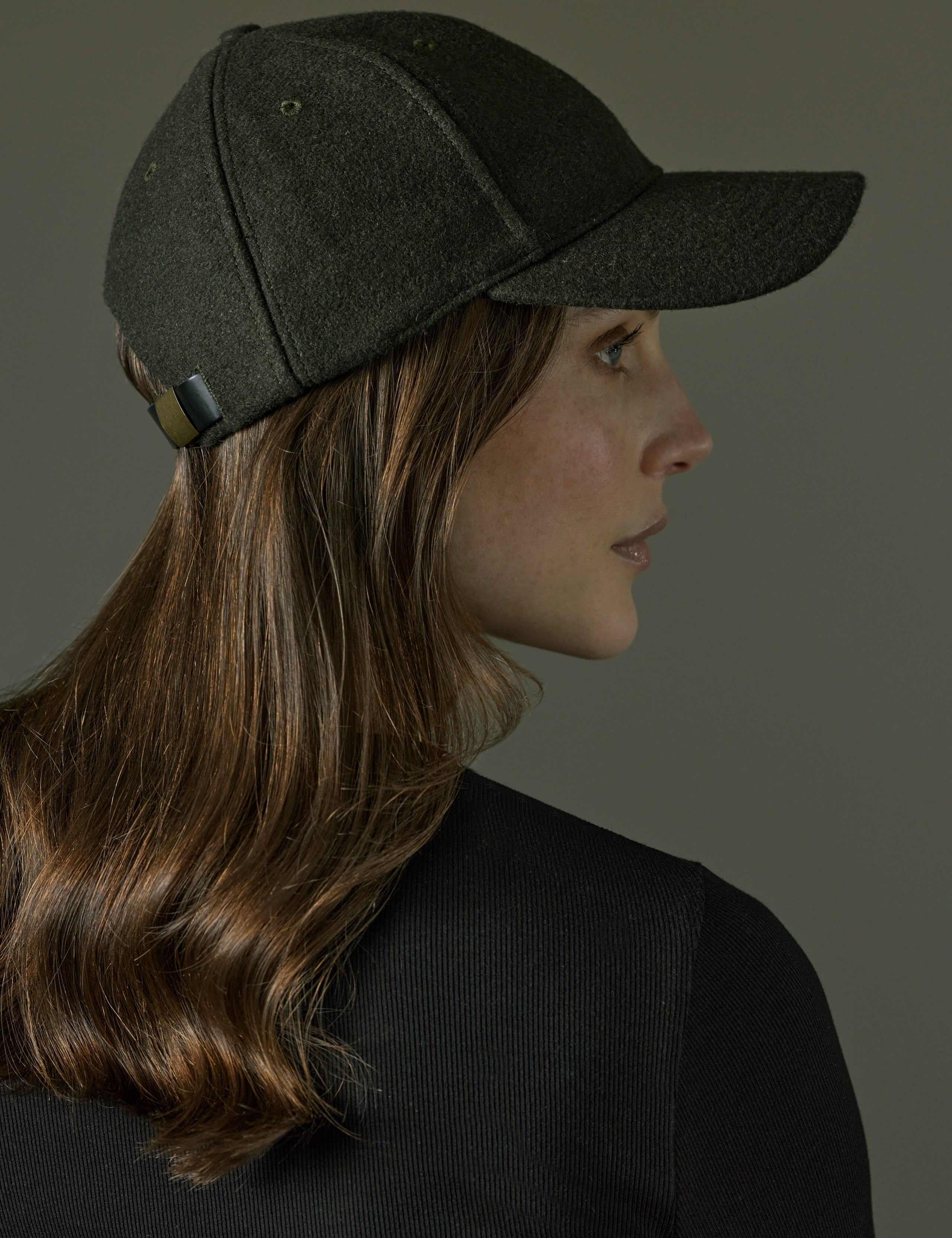 Side profile view of woman wearing AETHER Wool Hat in Dark Command Green from AETHER Apparel.