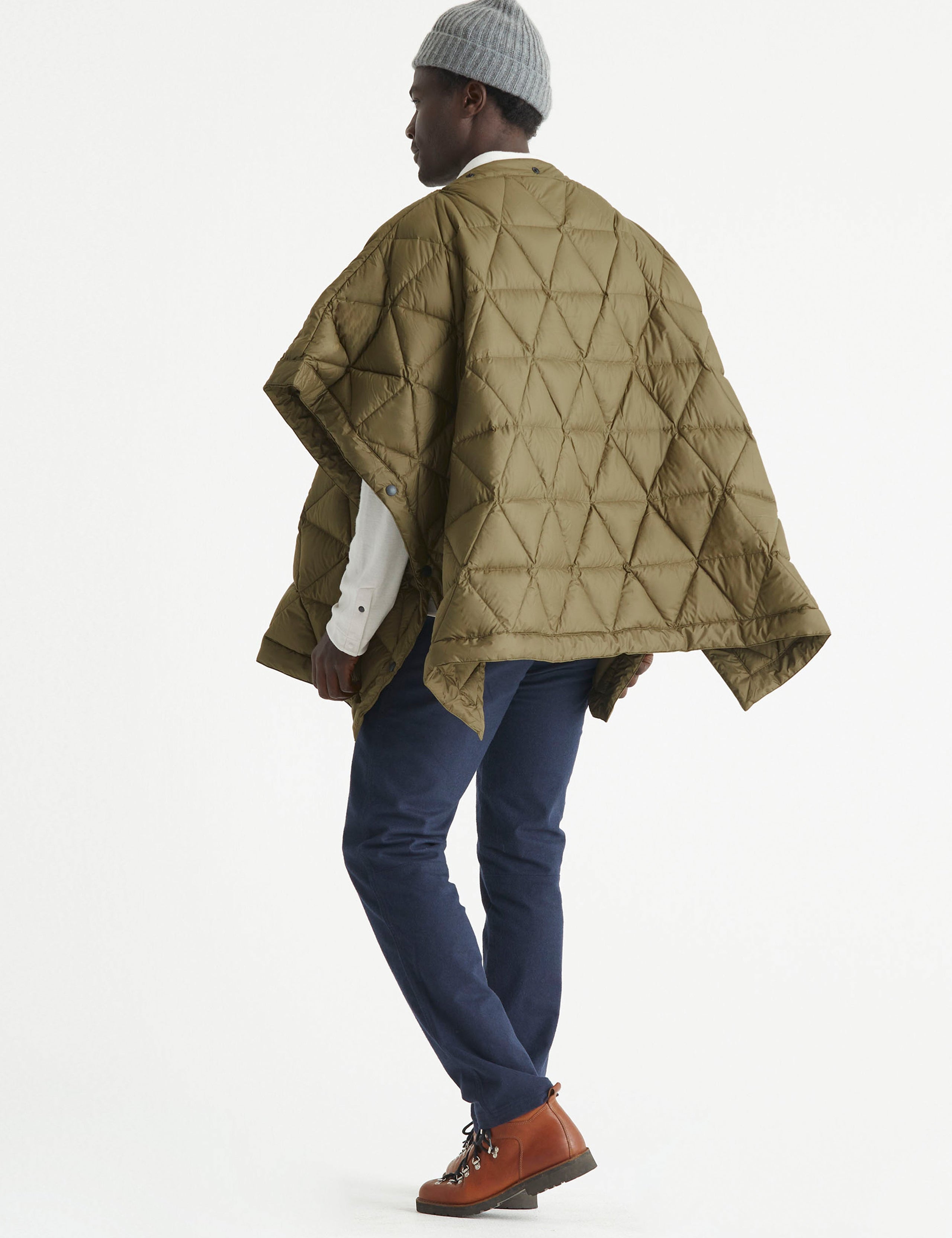 Rear 3/4 full-body view of man wearing Down Poncho in Command Green from AETHER Apparel.