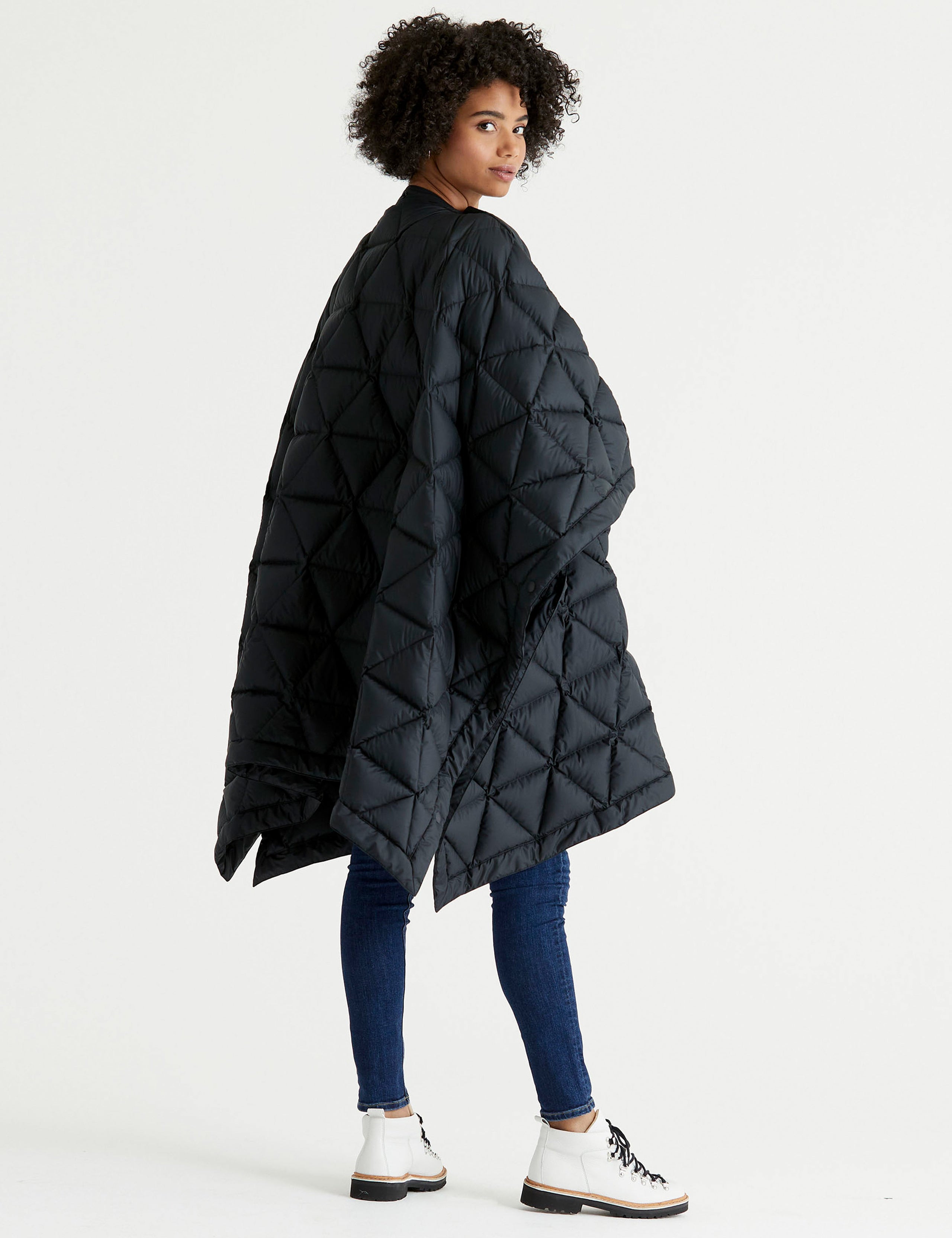 Rear 3/4 full-body view of woman wearing Down Poncho in Onyx Black from AETHER Apparel.