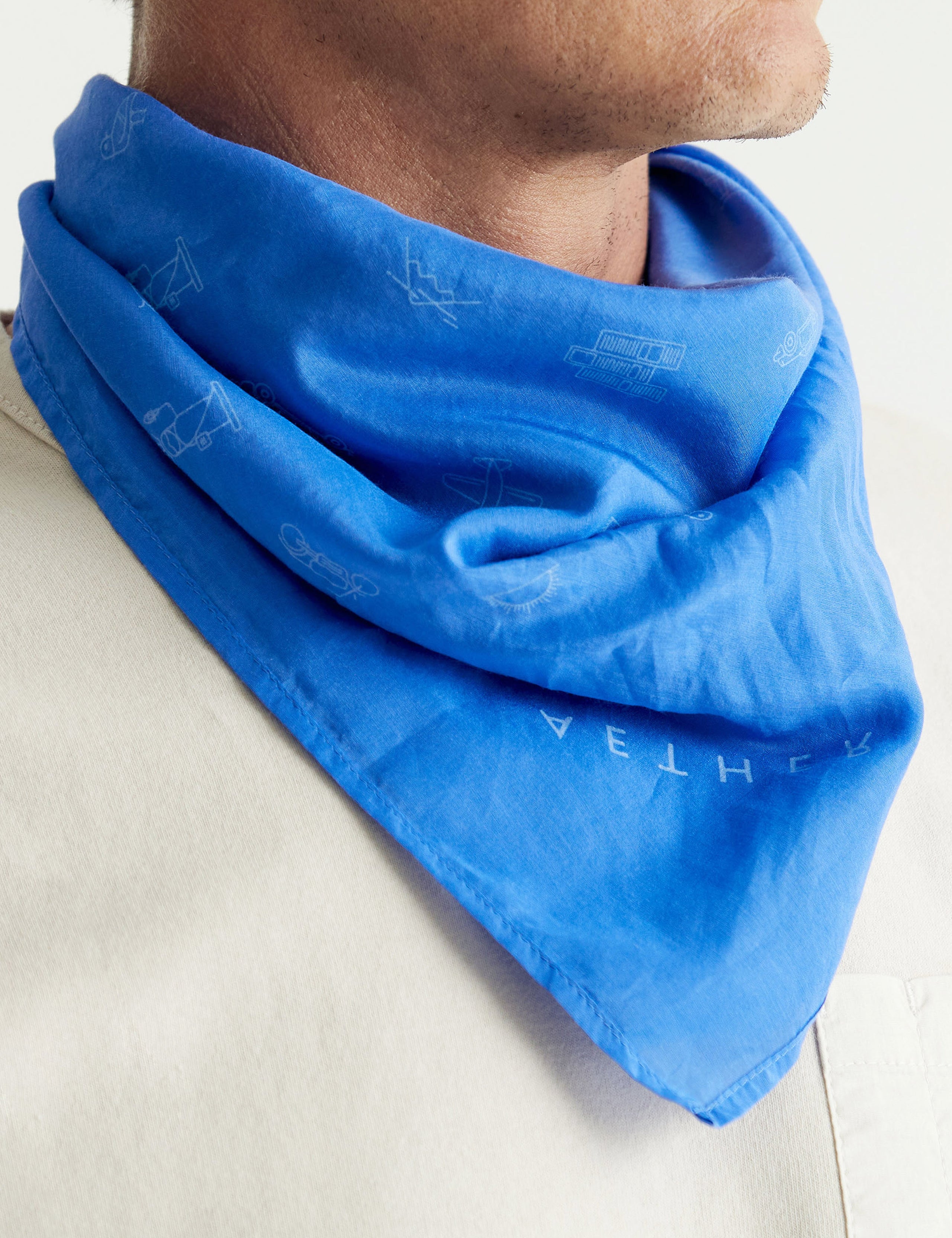 Closeup front angled view of man wearing Lifestyle Bandana in Royal Blue from AETHER Apparel around neck. 