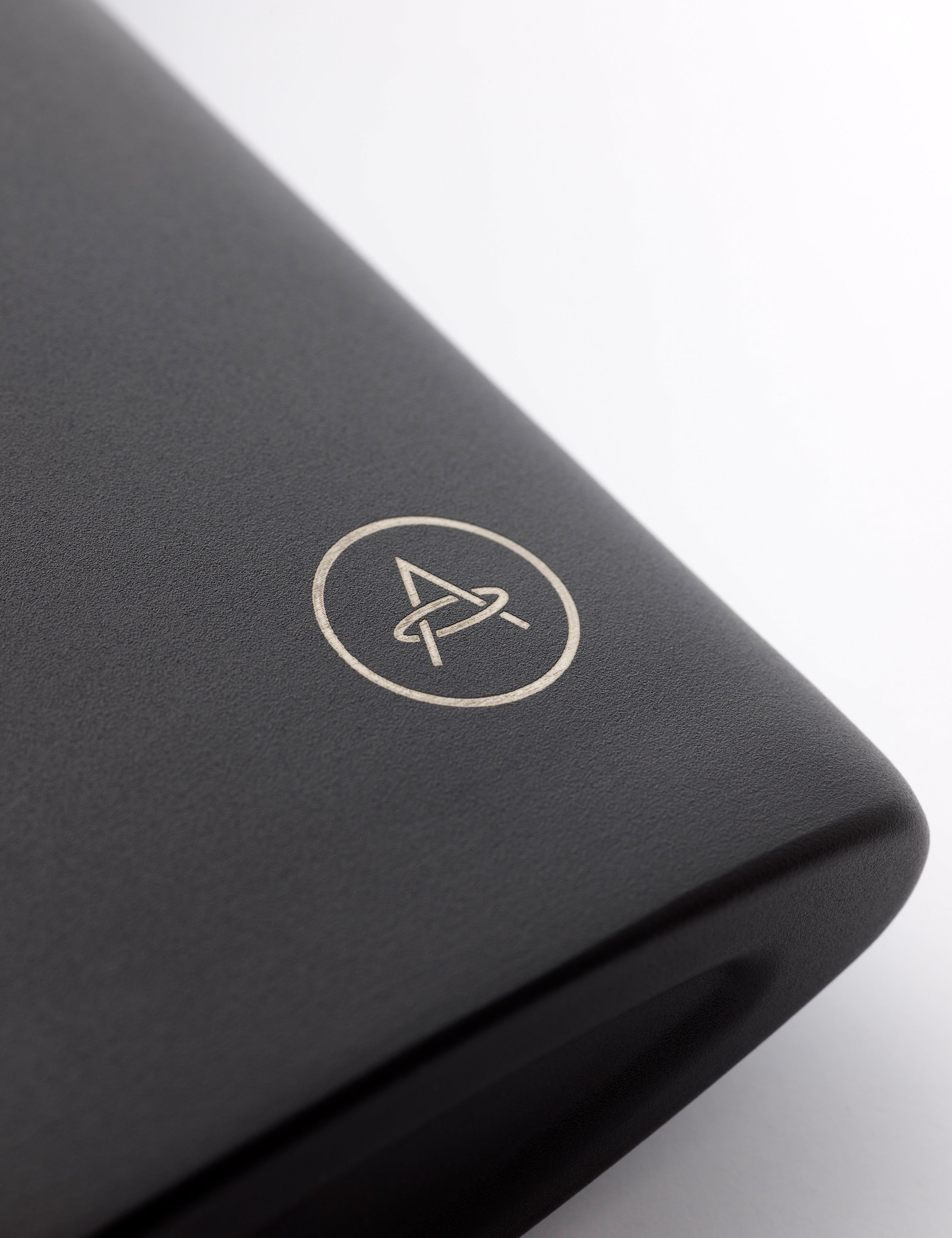 Closeup detailed view of AETHER logo on bottom corner of AETHER + Miir Aero Flask in Black with top open.