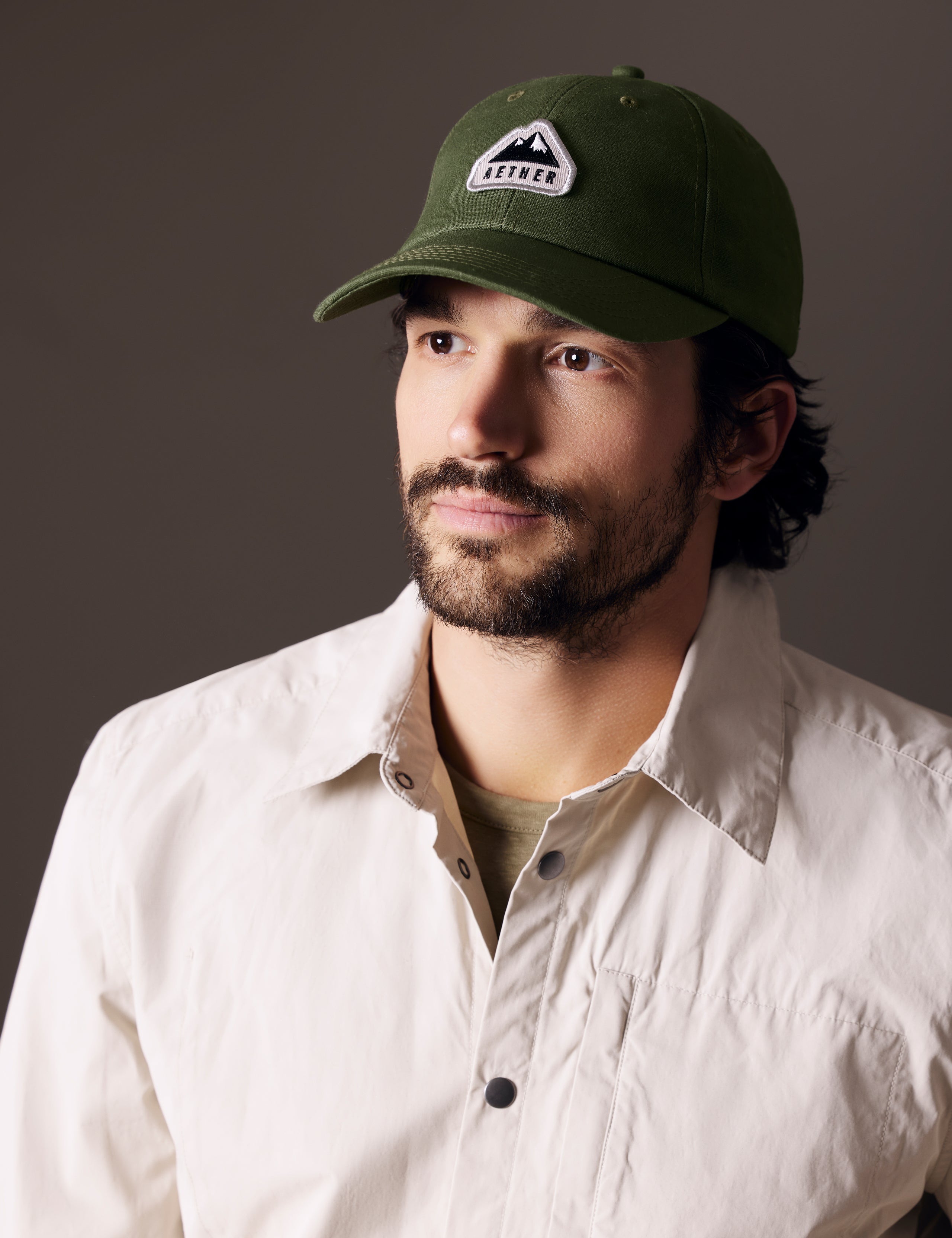 Front angled view of man wearing AETHER Mountain Hat in Army Green from AETHER Apparel.