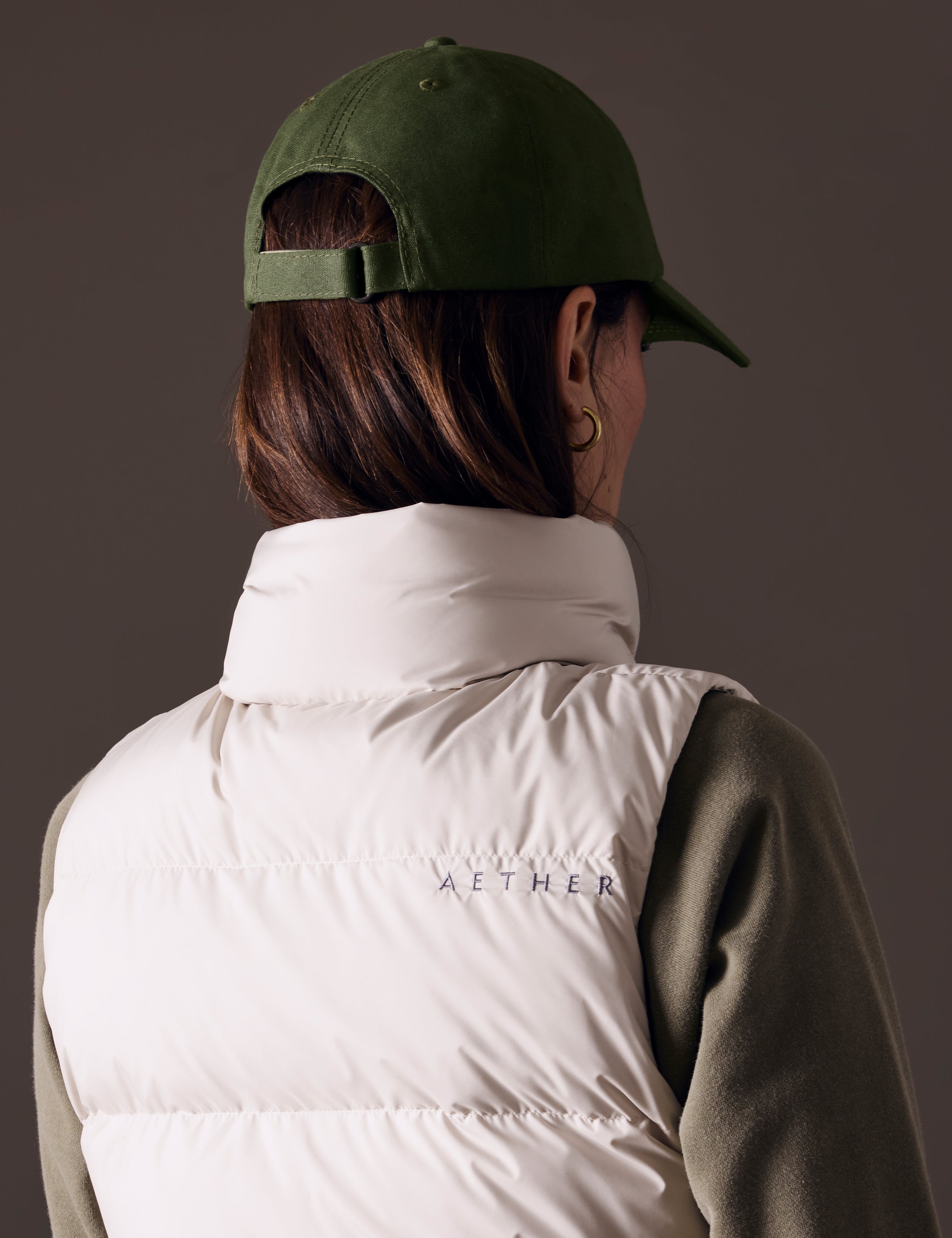 Rear angled view of woman wearing AETHER Mountain Hat in Army Green from AETHER Apparel. 