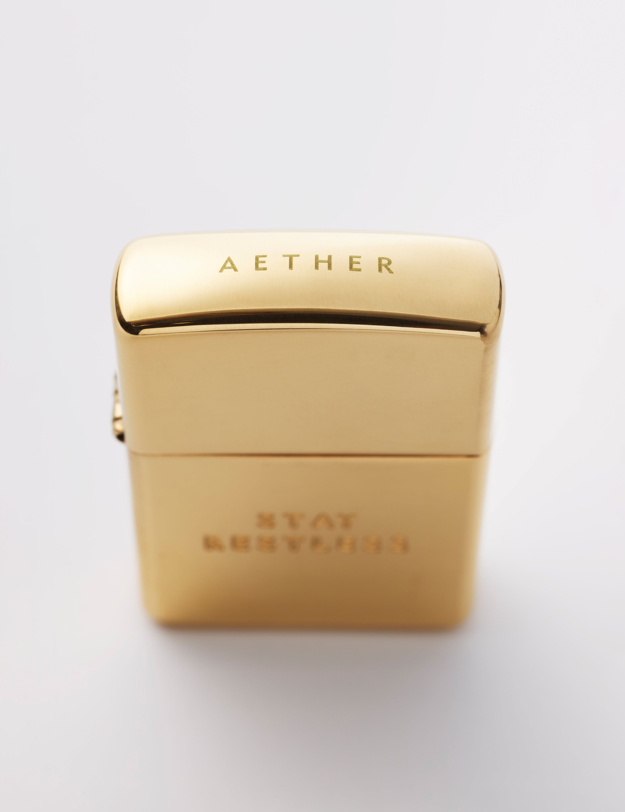 Top angled view of AETHER logo on cap of Restless Zippo Lighter in high polish brass from AETHER Apparel with top closed. 