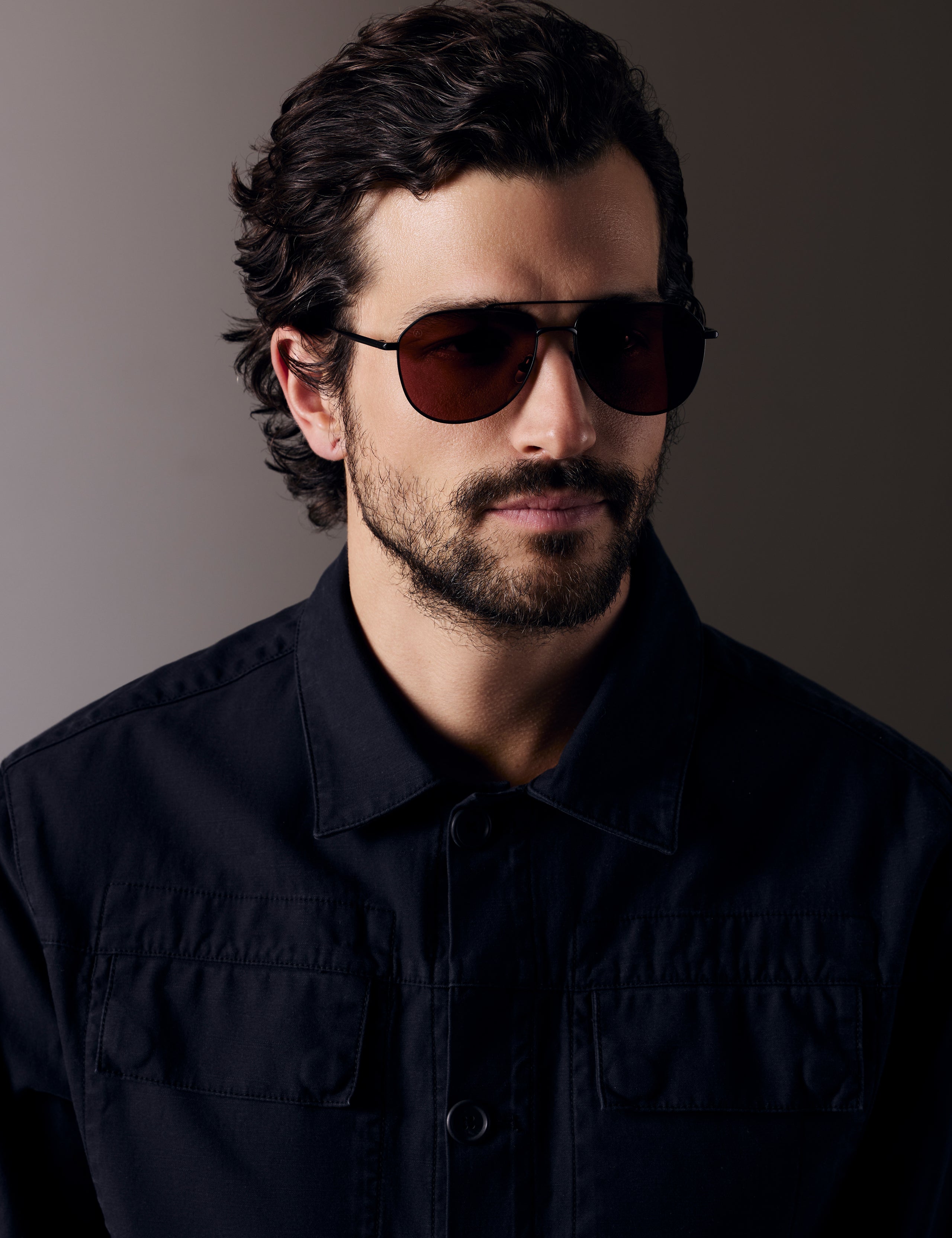 Front right 3/4 view of man wearing Bryce Sunglass in black titanium with Red Lens from AETHER Apparel.