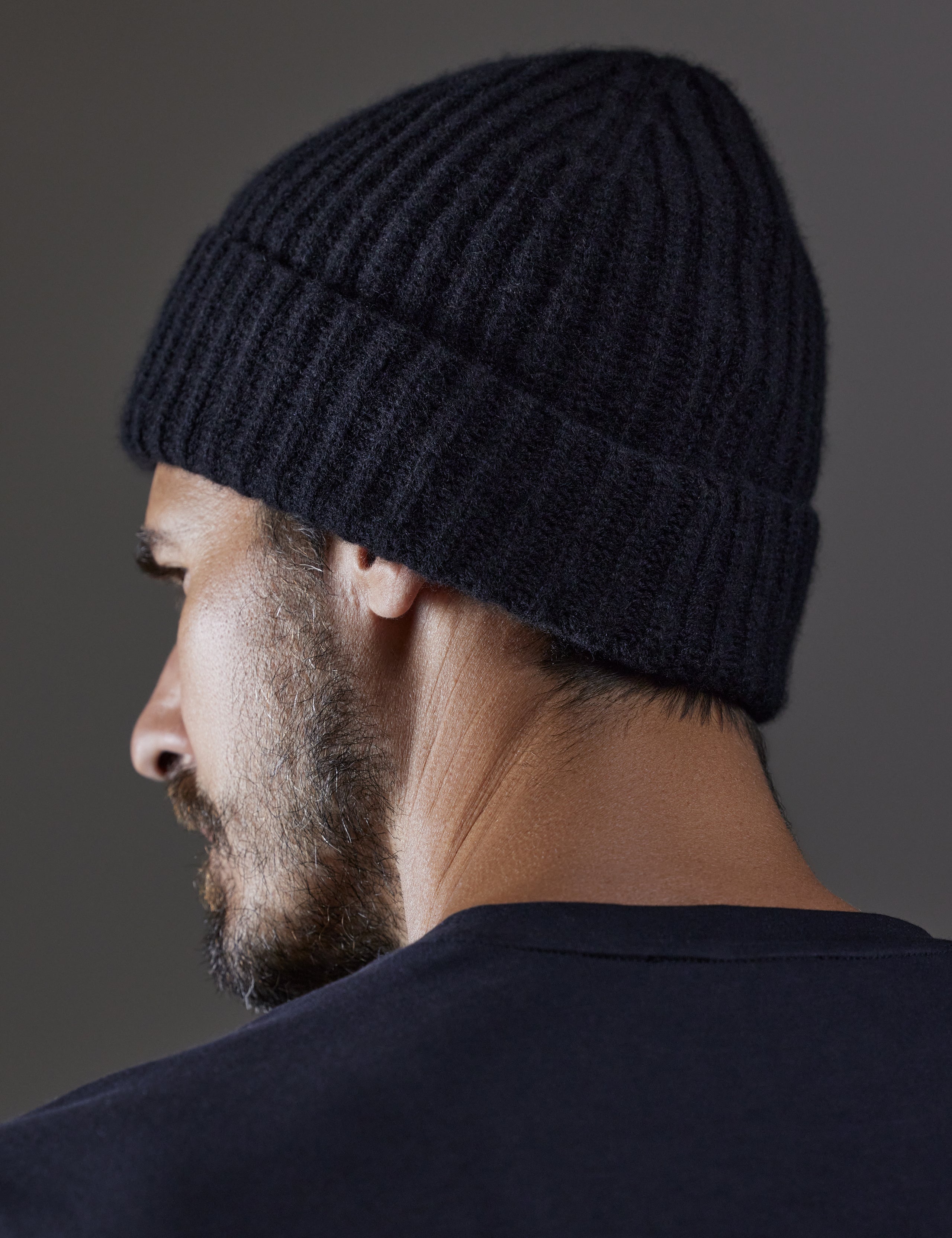 Rear angled view of man wearing Cashmere Hat in Onyx Black from AETHER Apparel. 
