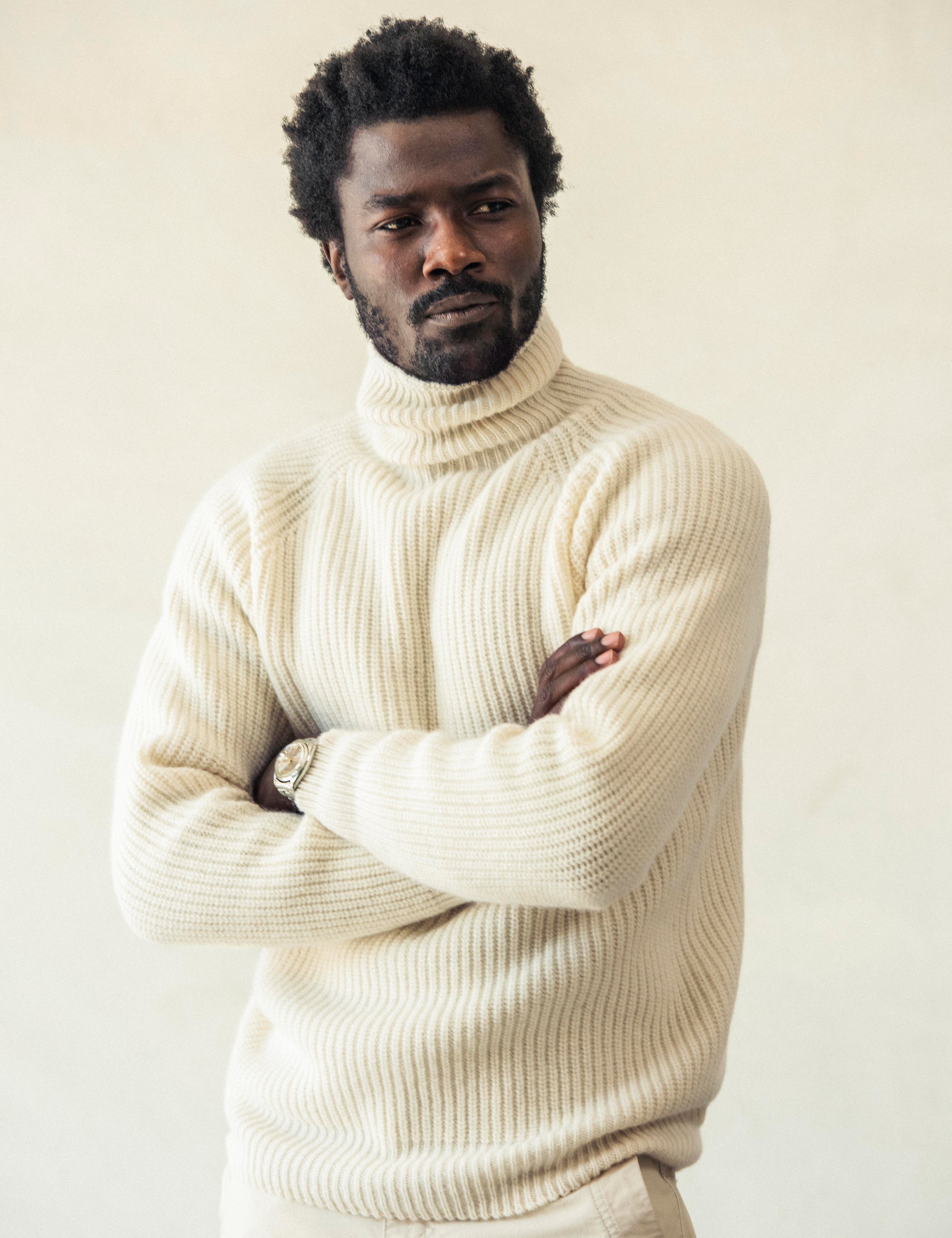 Front angled view of man with arms crossed wearing Finley Sweater in Winter White from AETHER Apparel.