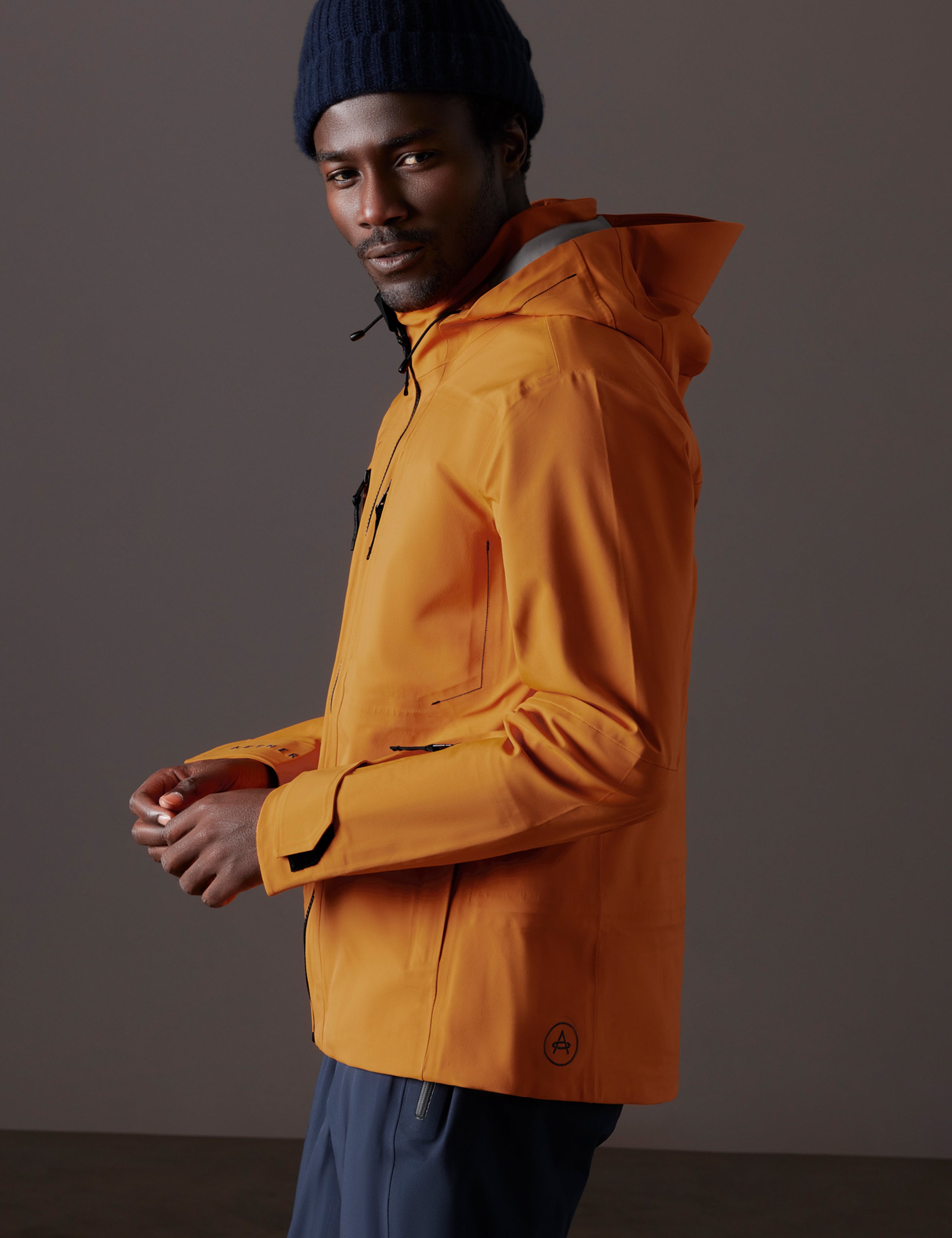 Side profile body view of man wearing Altitude Snow Shell 2.0 in Autumn Orange from AETHER Apparel.