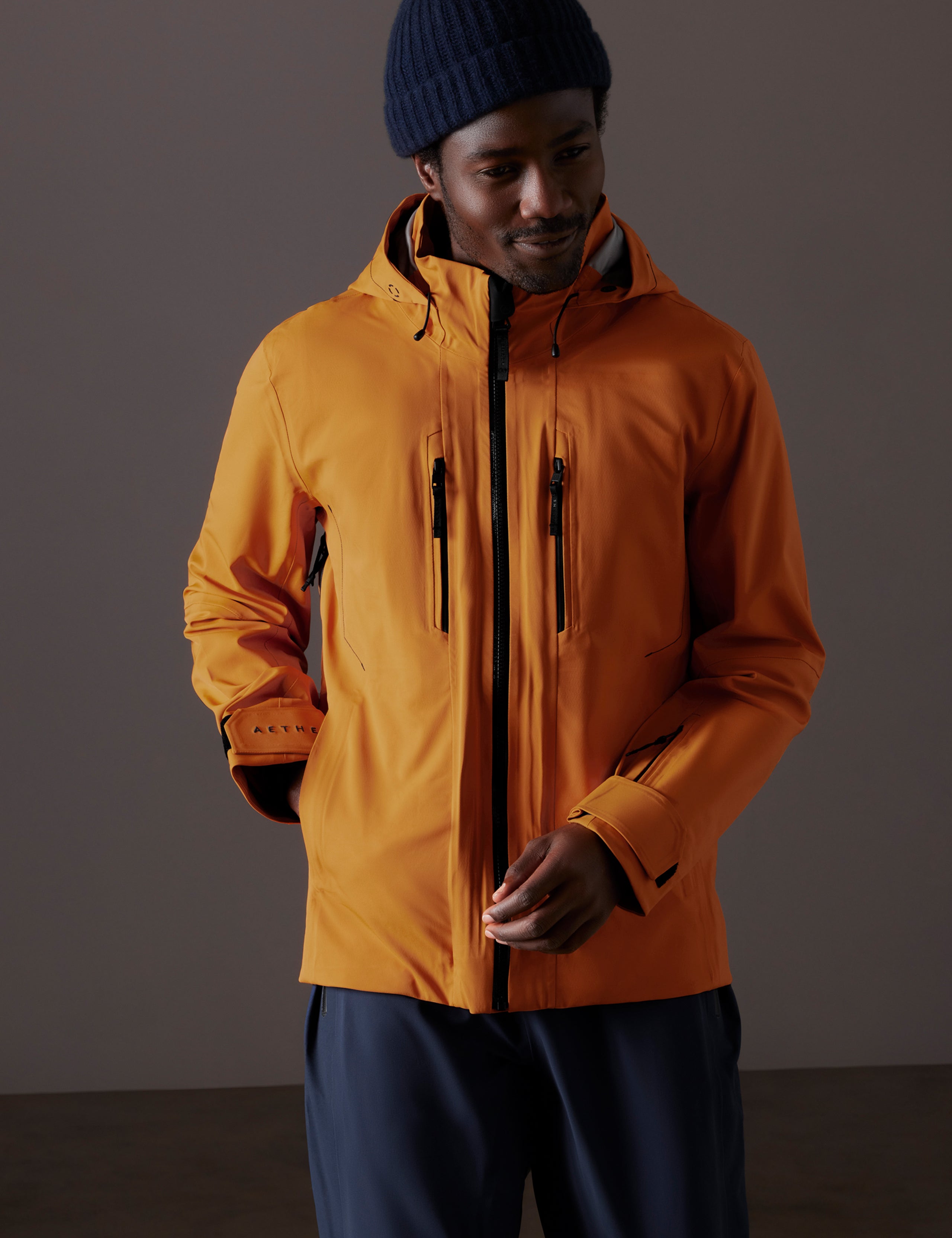 Front body view of man wearing Altitude Snow Shell 2.0 in Autumn Orange from AETHER Apparel.