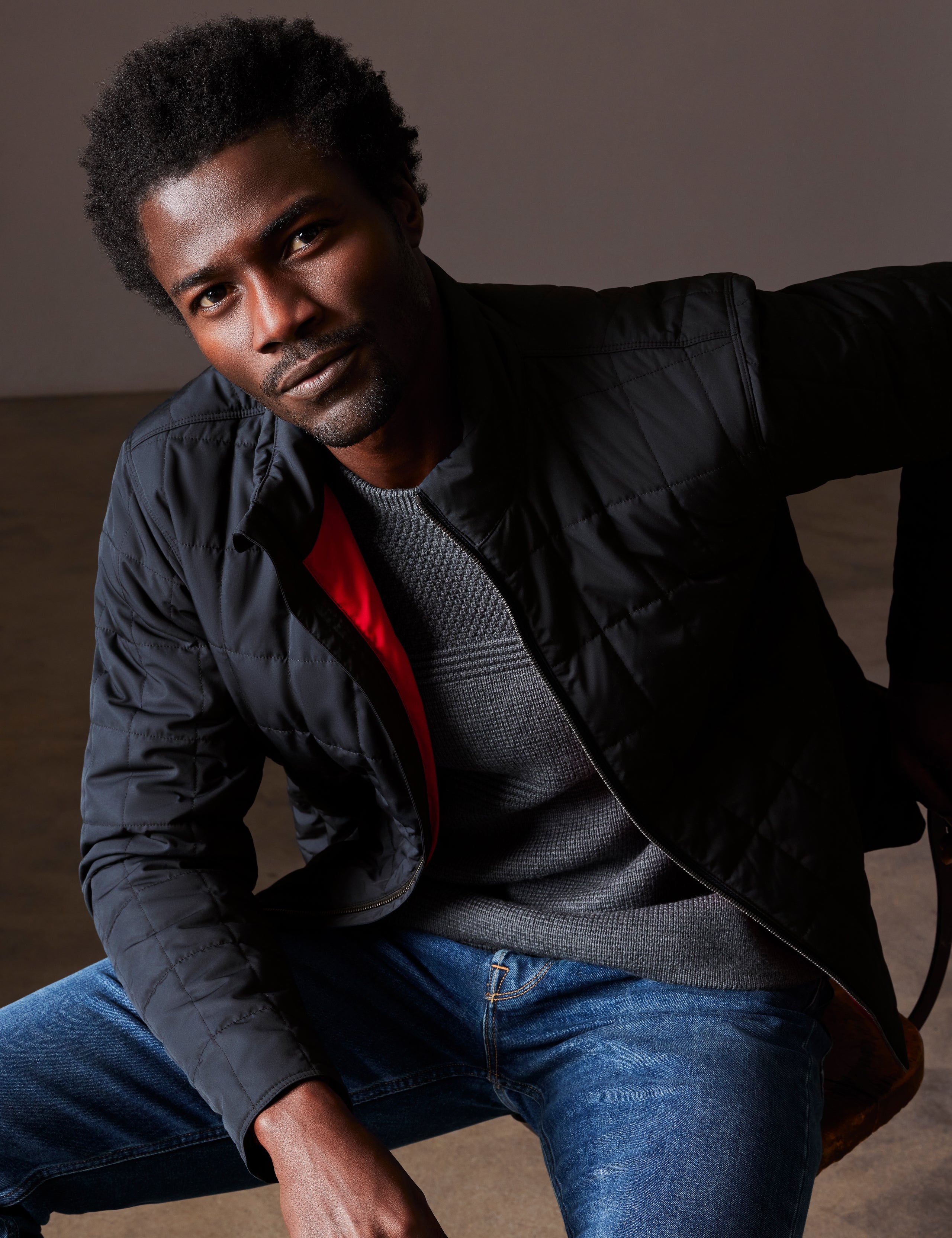 Front 3/4 body view of man sitting wearing Alto Jacket in Onyx Black from AETHER Apparel.