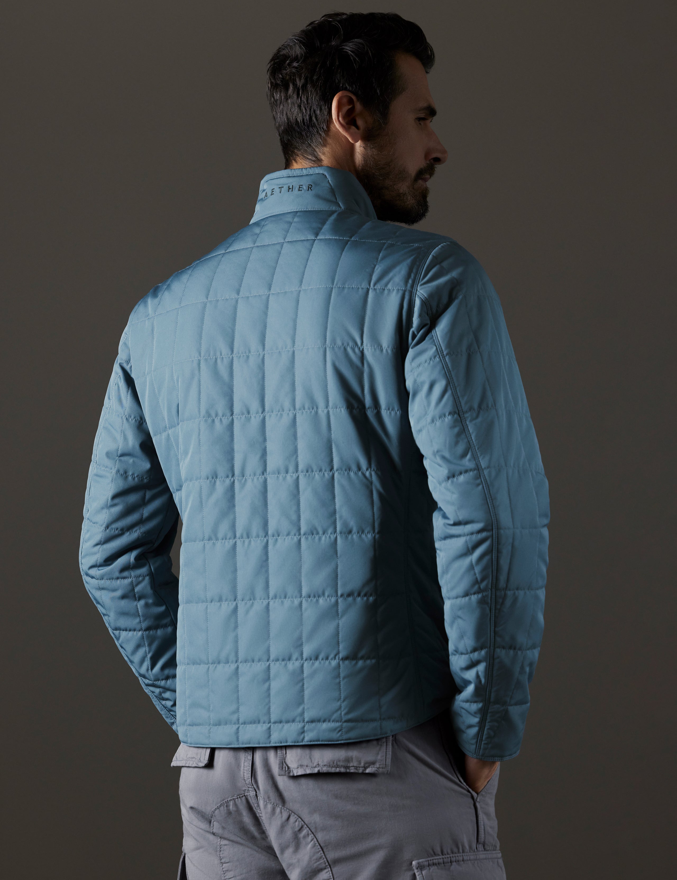 Rear 3/4 body view of man wearing Alto Jacket in Portal Blue from AETHER Apparel.
