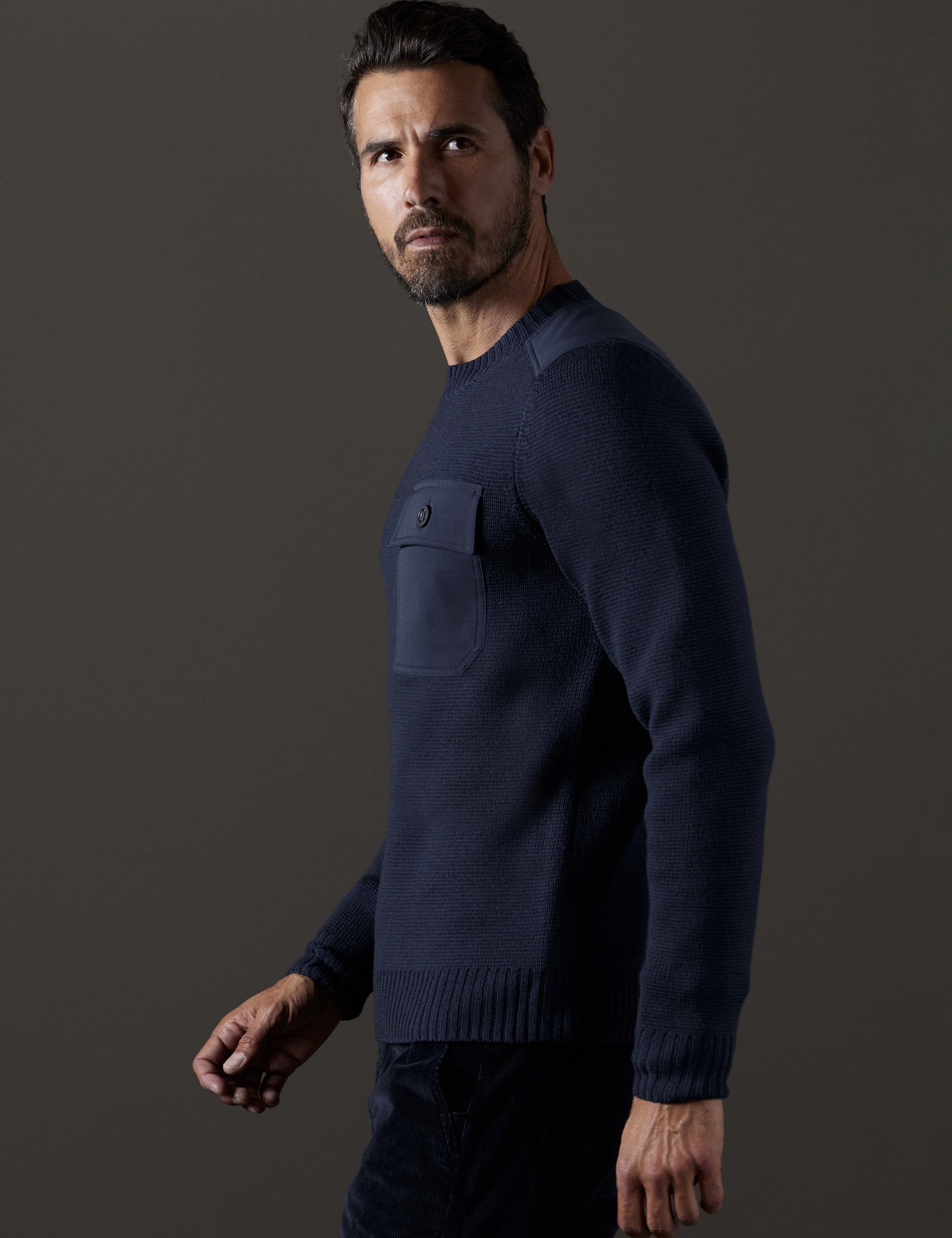 Side profile body view of man wearing Benson Crewneck Sweater in Total Eclipse dark blue from AETHER Apparel.