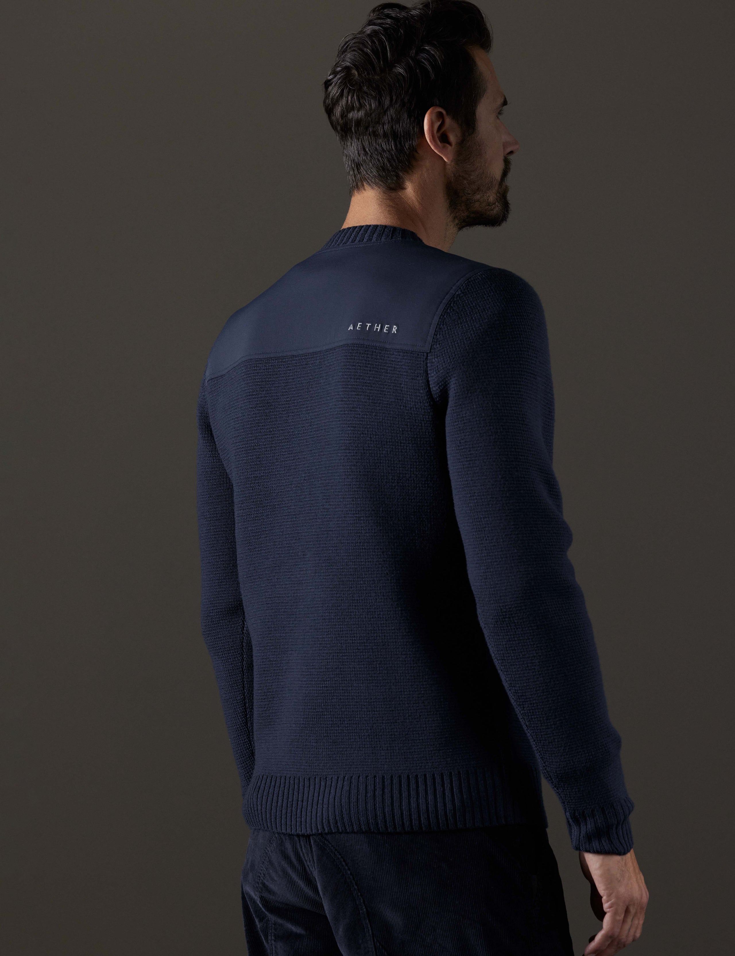 Rear 3/4 body view of man wearing Benson Crewneck Sweater in Total Eclipse dark blue from AETHER Apparel.