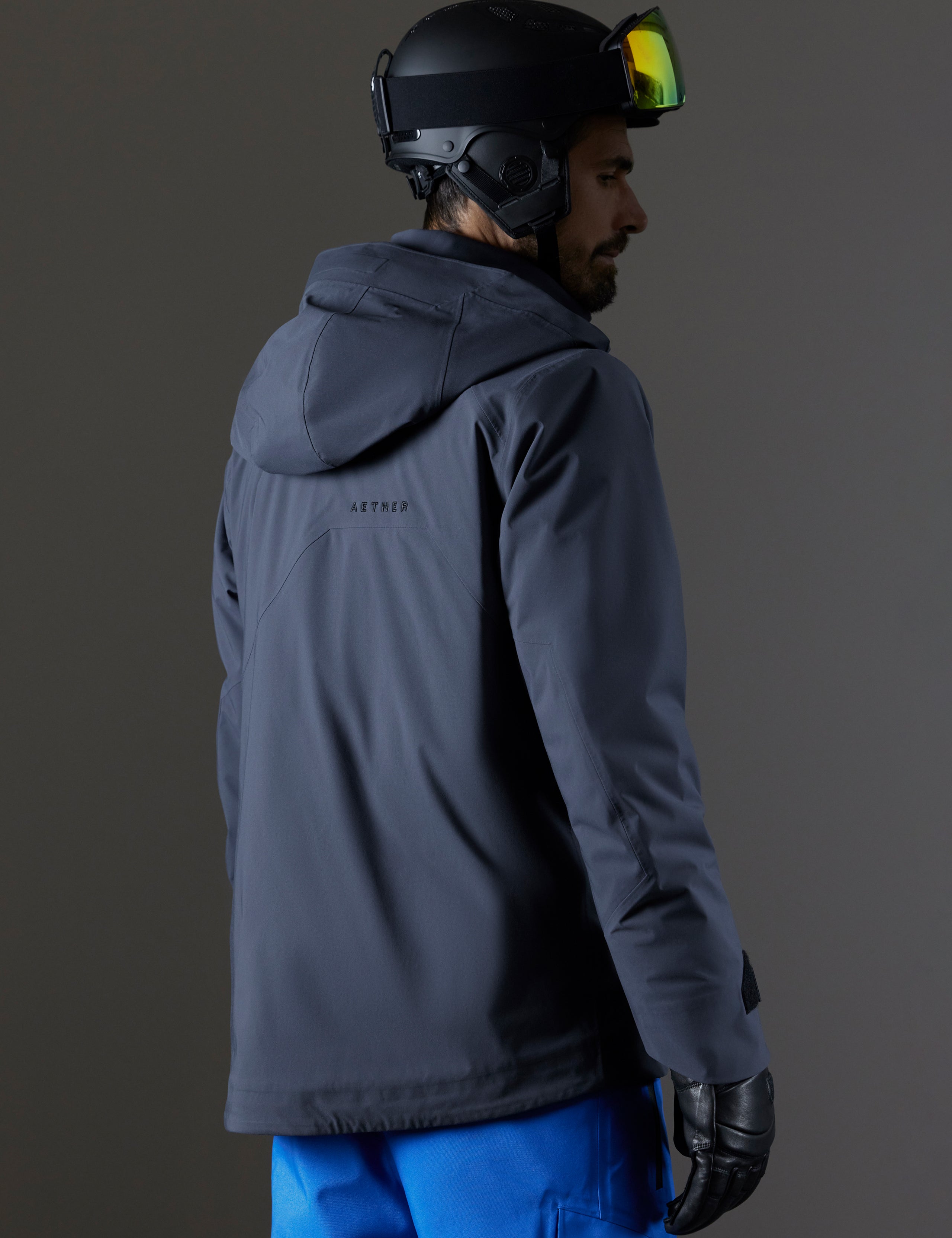 Rear 3/4 body view of man wearing Brighton Insulated Snow Jacket in Graphite from AETHER Apparel.