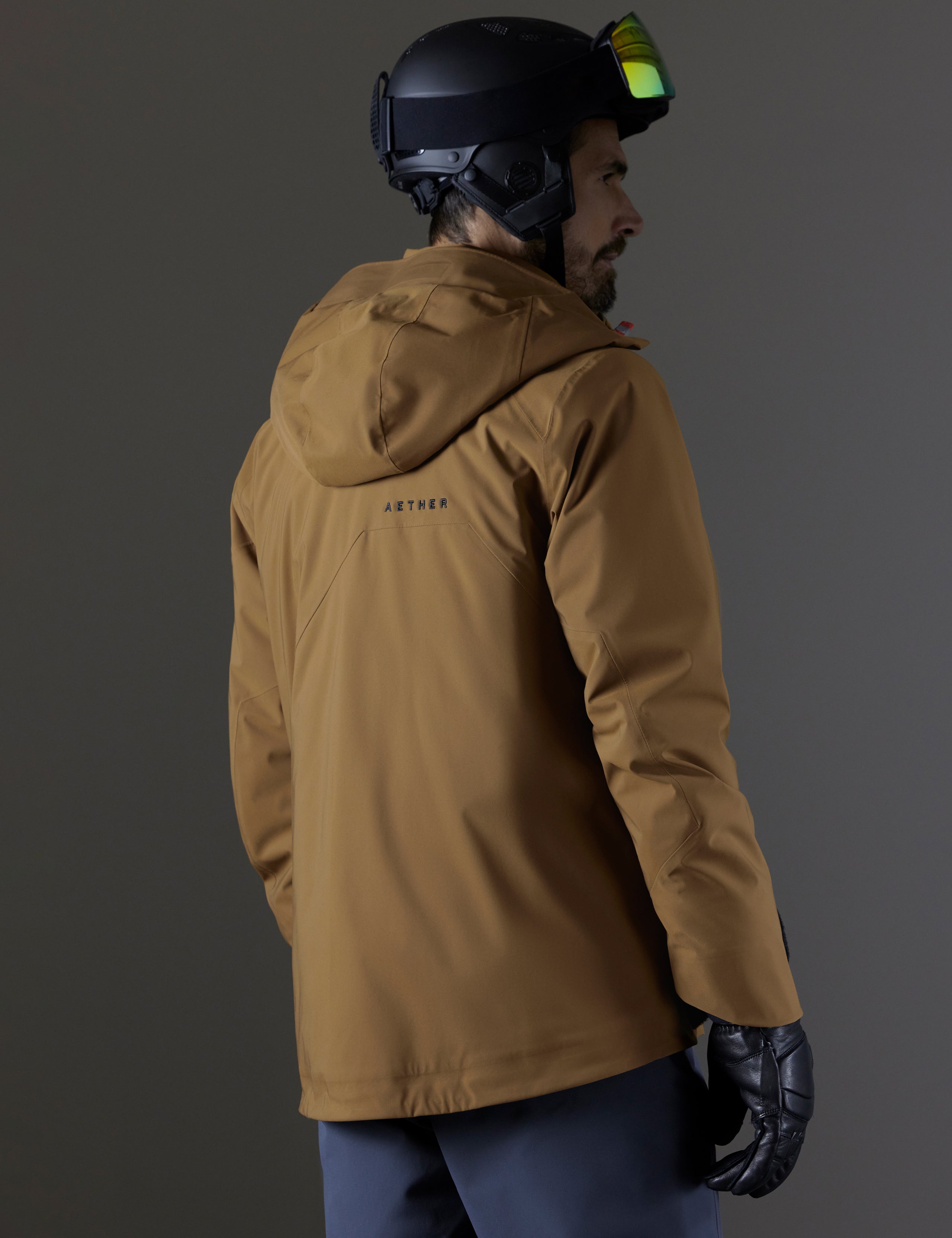 Rear 3/4 body view of man wearing Brighton Insulated Snow Jacket in Rubber Brown from AETHER Apparel.