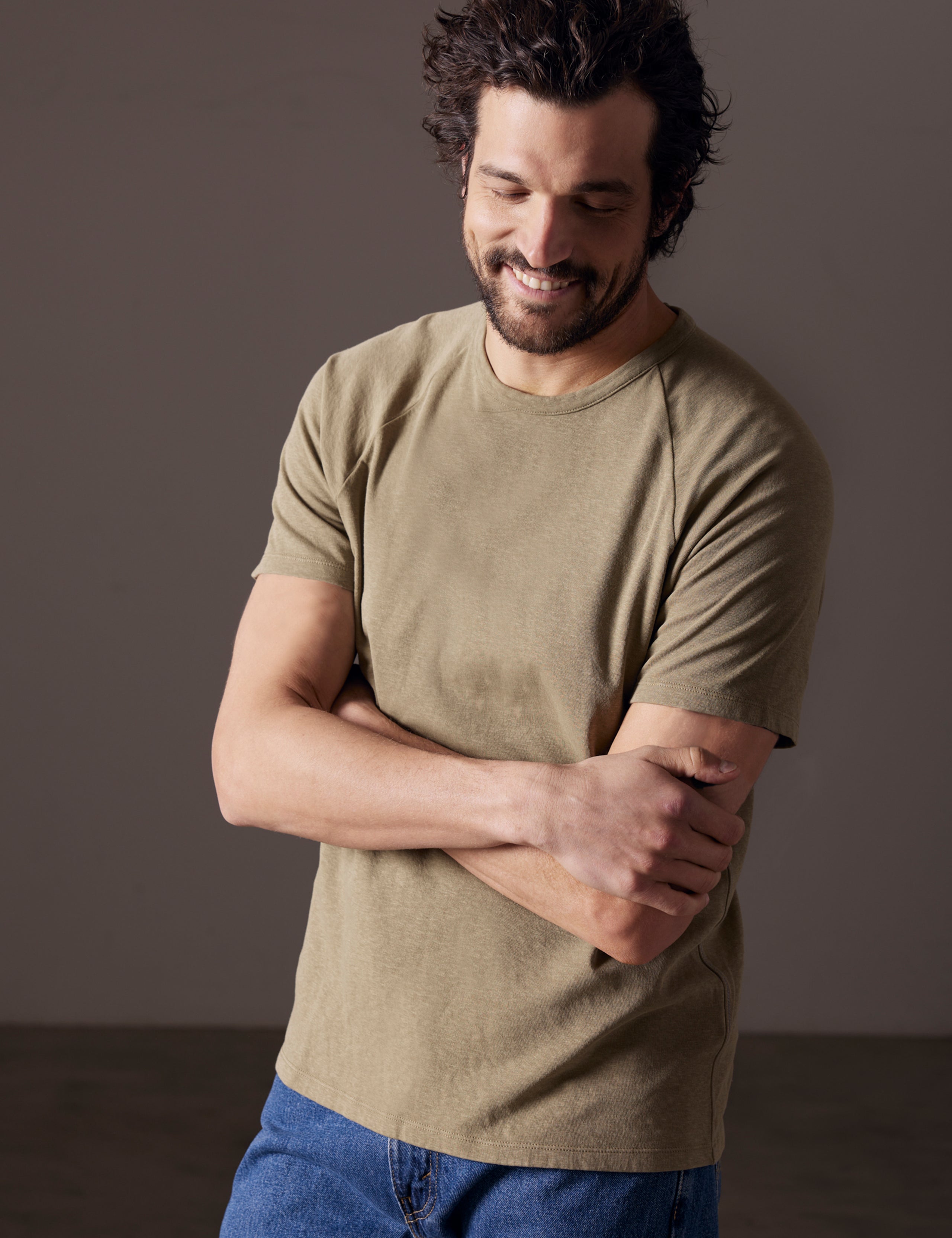 Front angled body view of man with arms crossed wearing Buckhorn Cotton Raglan Tee in Mineral Green from AETHER Apparel.