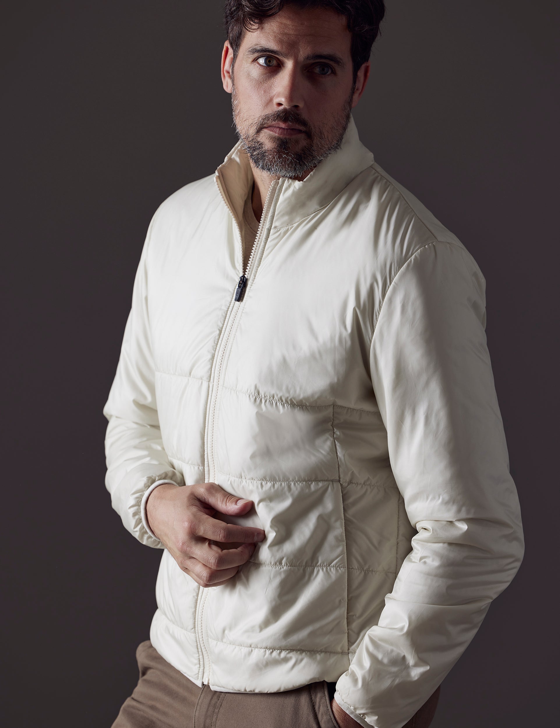 Front 3/4 body view of man with hand in pant pocket wearing Eco Insulated Jacket in Winter White from AETHER Apparel.