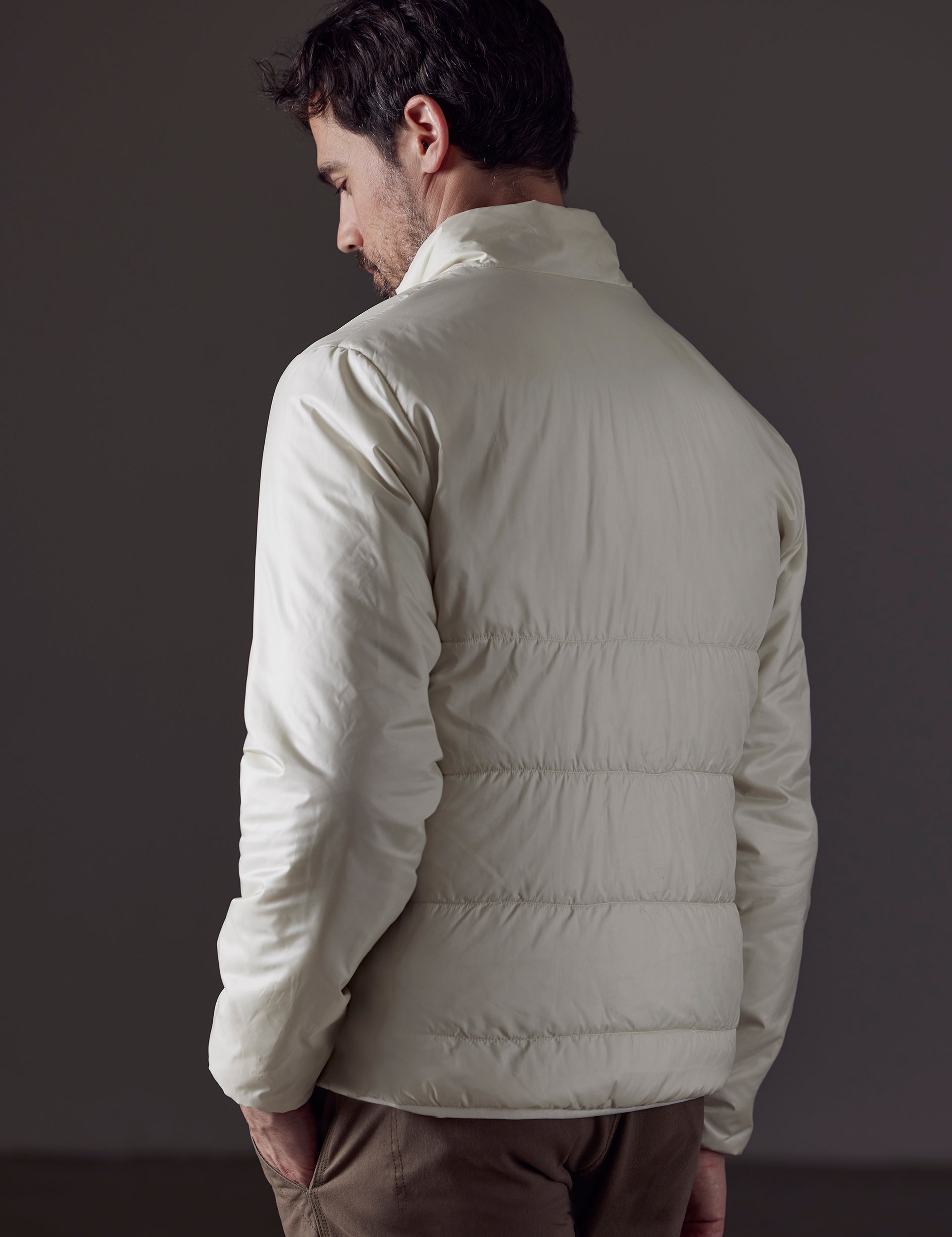 Rear 3/4 body view of man wearing Eco Insulated Jacket in Winter White from AETHER Apparel.