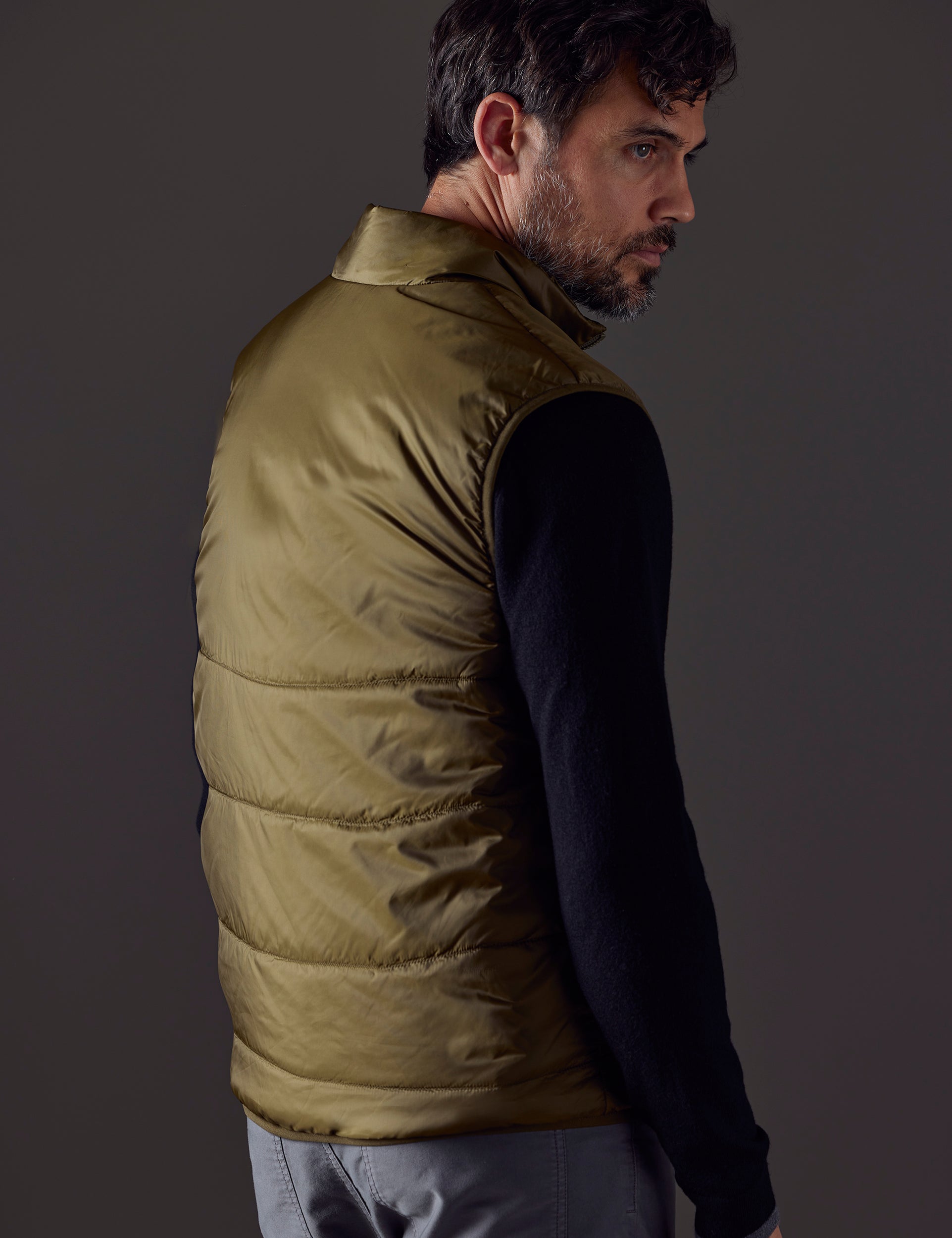 Rear 3/4 body view of man wearing Eco Insulated Vest in Command Green from AETHER Apparel.