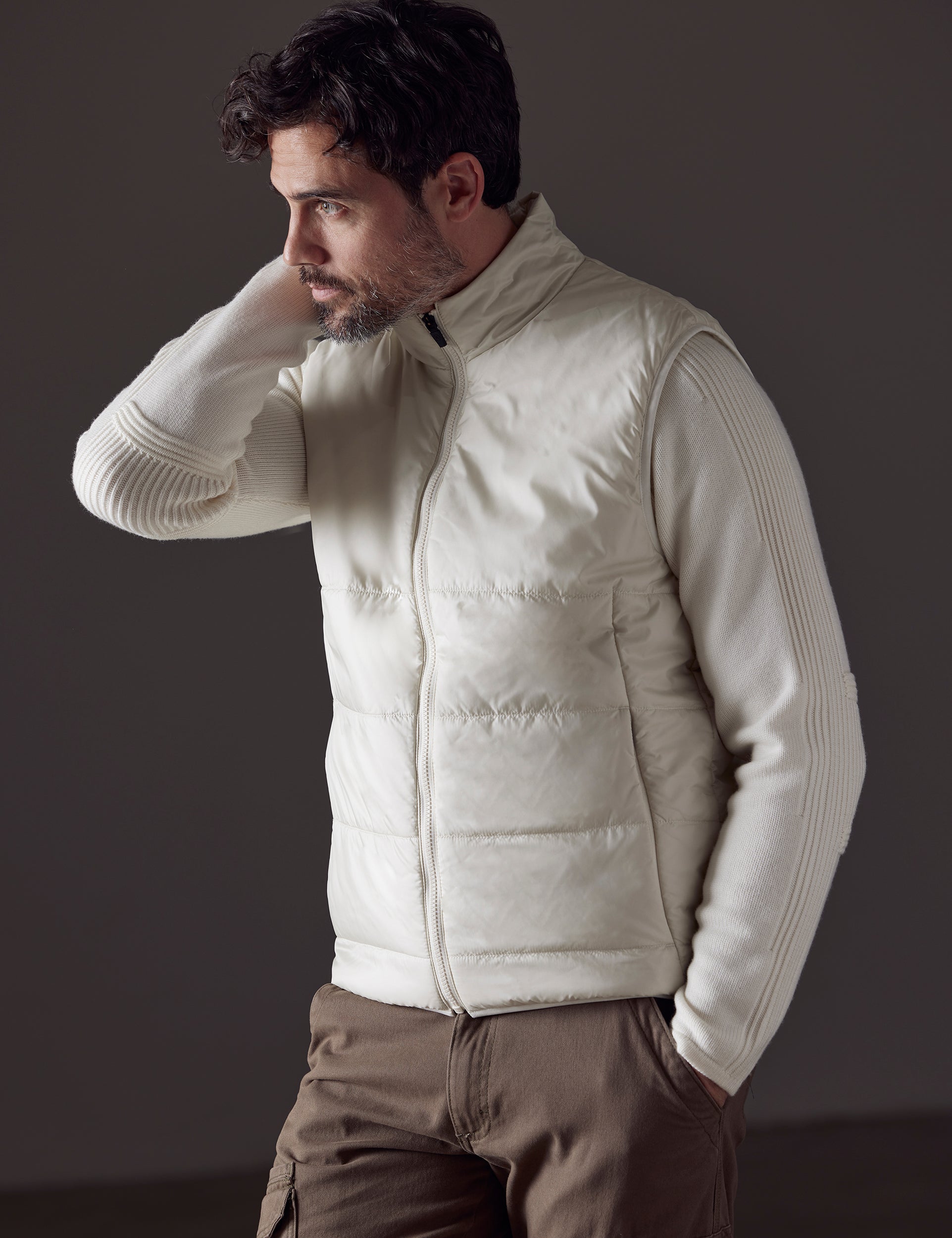 Front 3/4 body view of man with hand in pant pocket wearing Eco Insulated Vest in Winter White from AETHER Apparel.