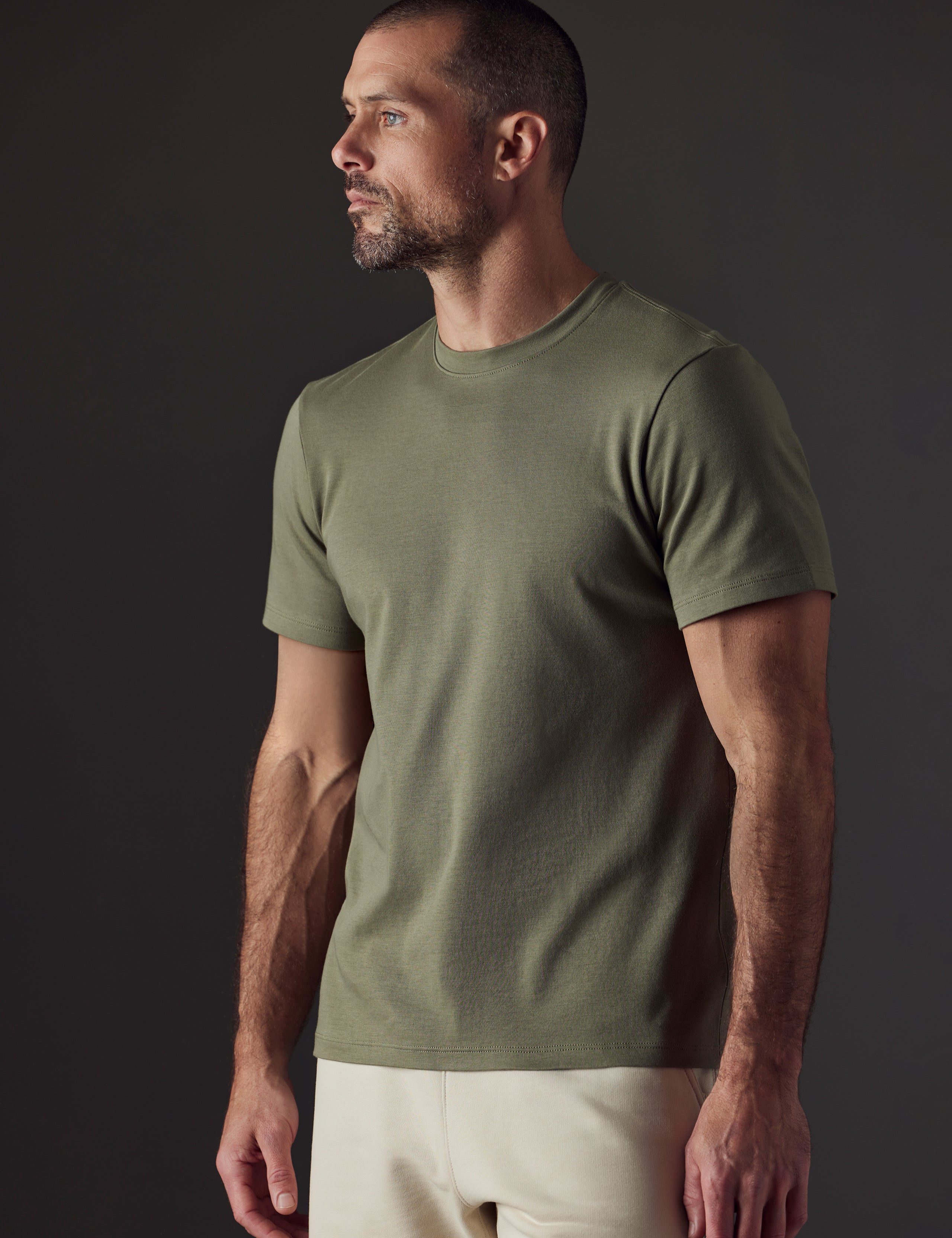 Front 3/4 body view of man wearing Emery Pima Crew Tee in Fern Green from AETHER Apparel.