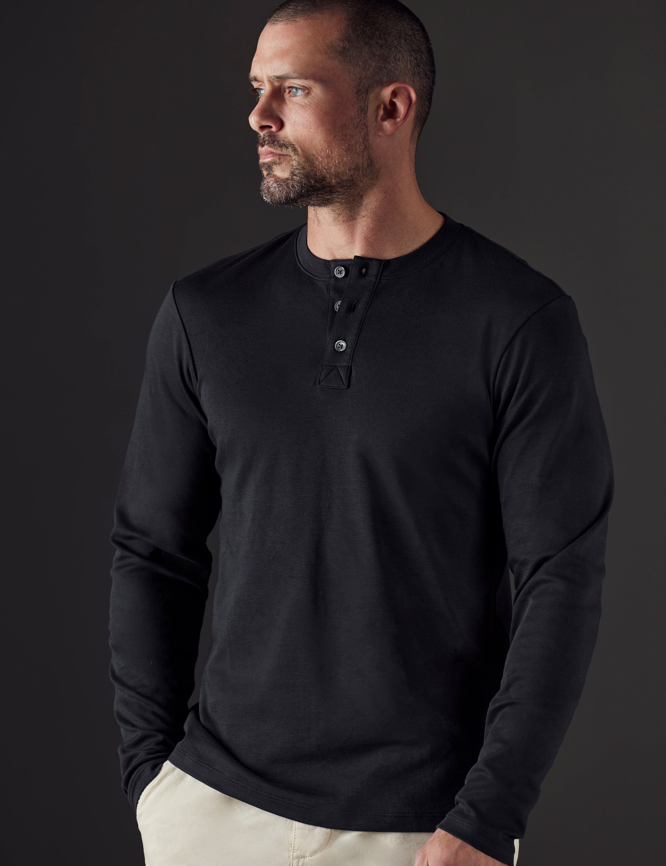Front body view of man wearing Emery Pima Henley in Onyx Black from AETHER Apparel.
