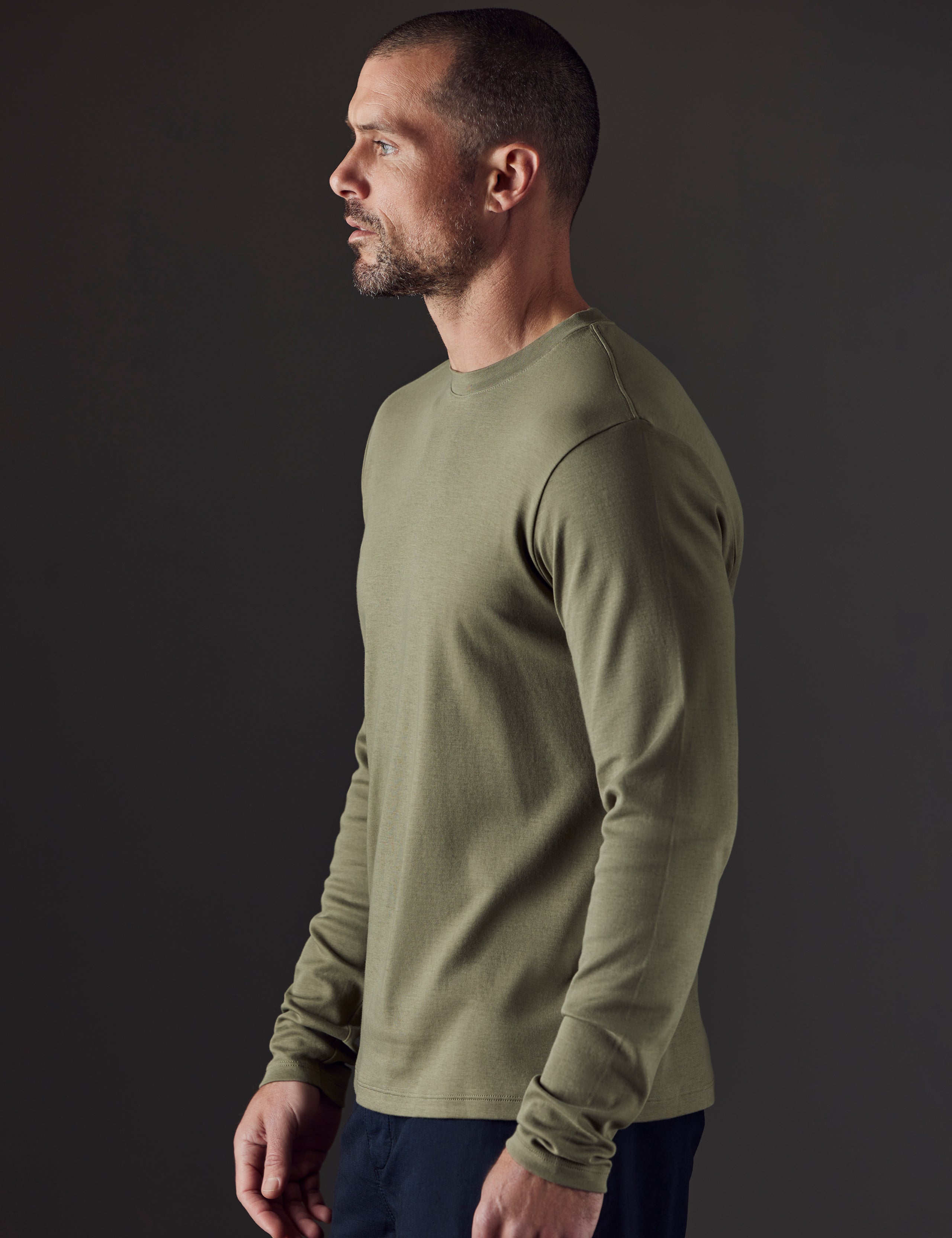 Side profile body view of man wearing Emery Pima Long-Sleeve Tee in Fern Green from AETHER Apparel.