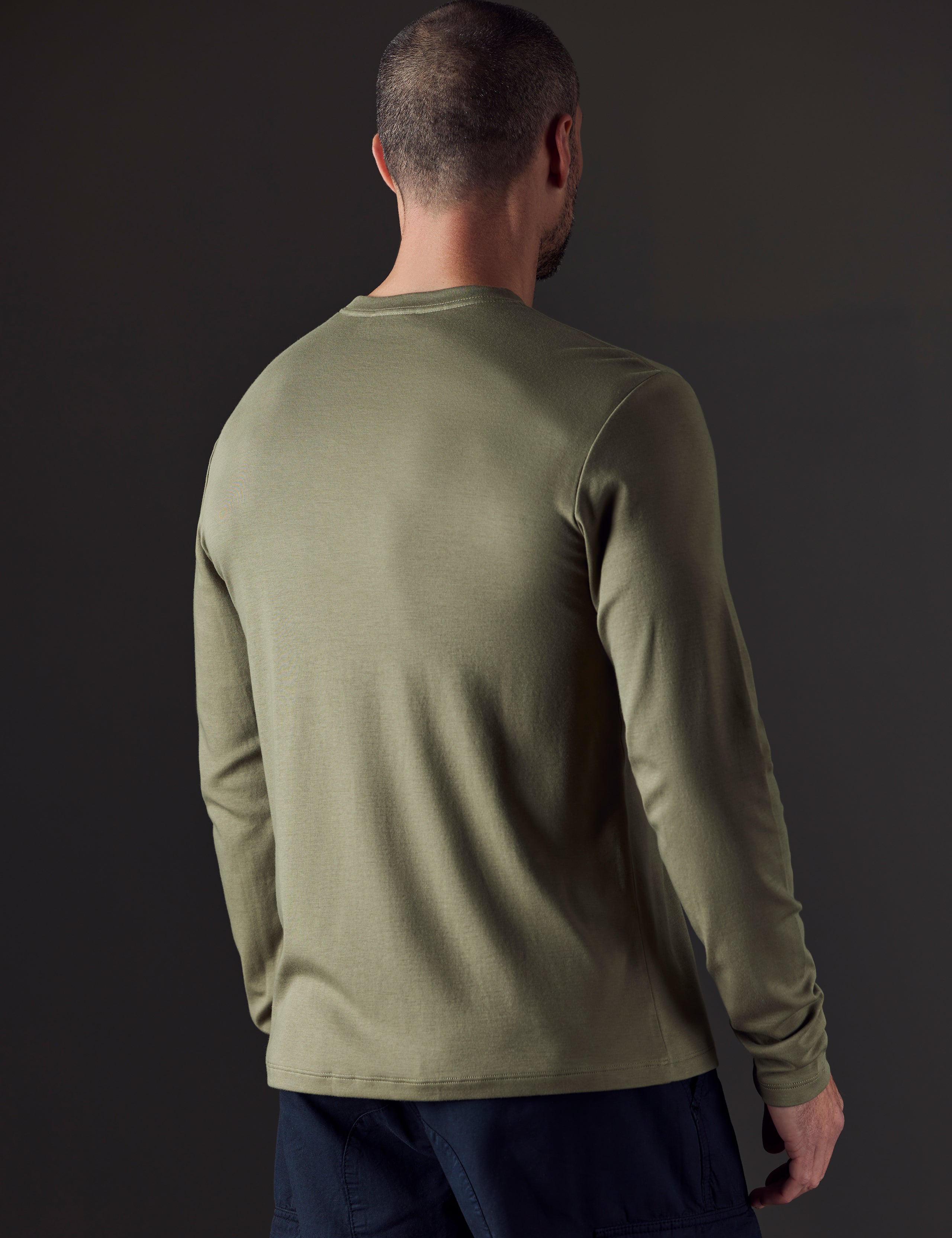 Rear 3/4 body view of man wearing Emery Pima Long-Sleeve Tee in Fern Green from AETHER Apparel.