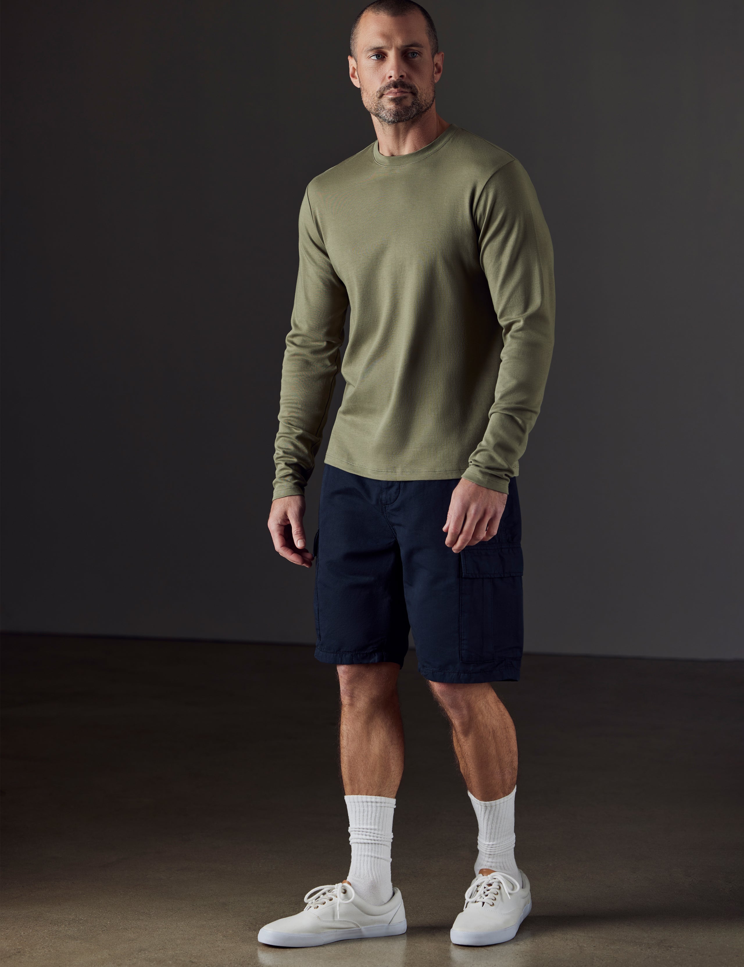 Front 3/4 full-body view of man wearing Emery Pima Long-Sleeve Tee in Fern Green from AETHER Apparel.