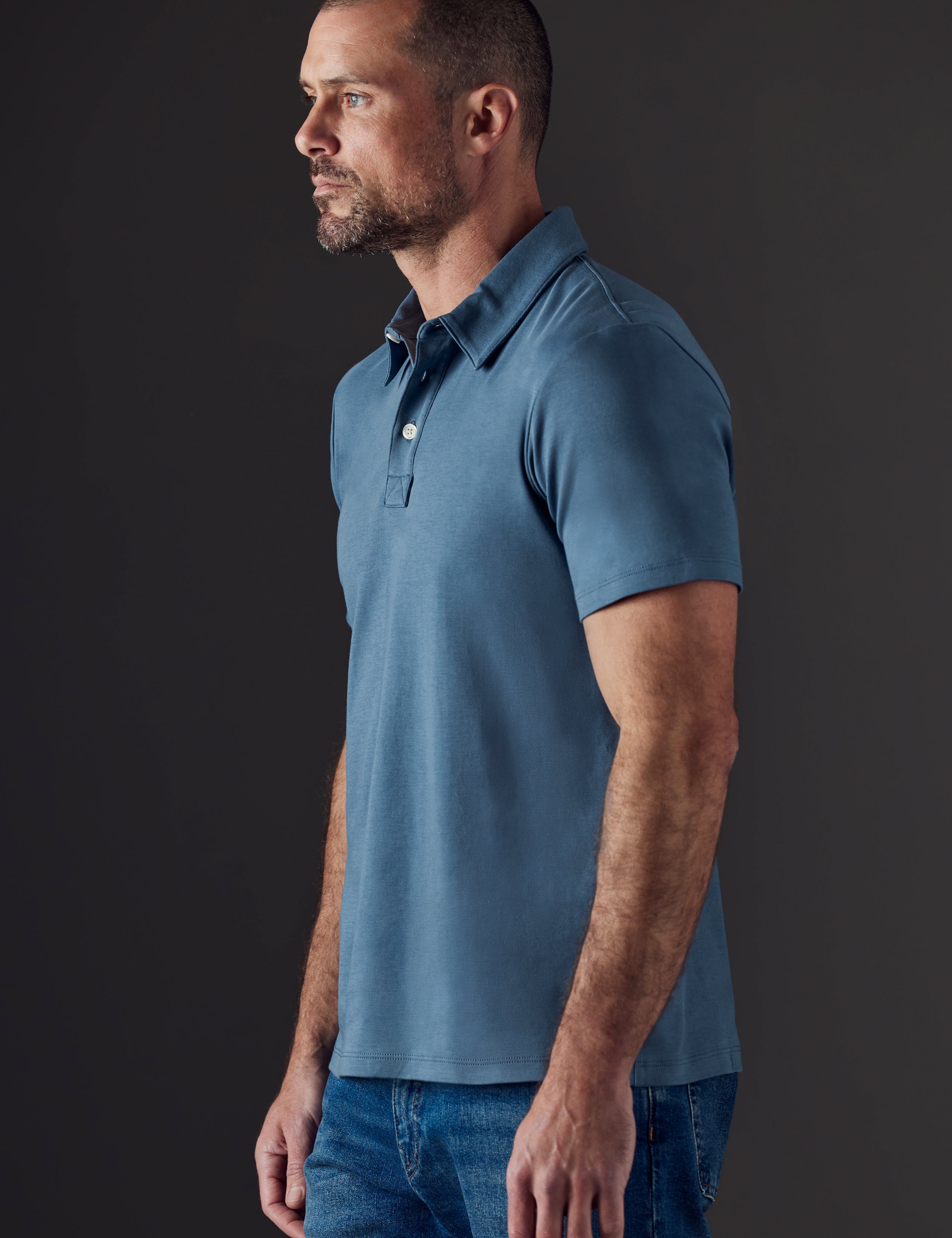 Side profile body view of man wearing Emery Pima Polo in Coastal Blue from AETHER Apparel.