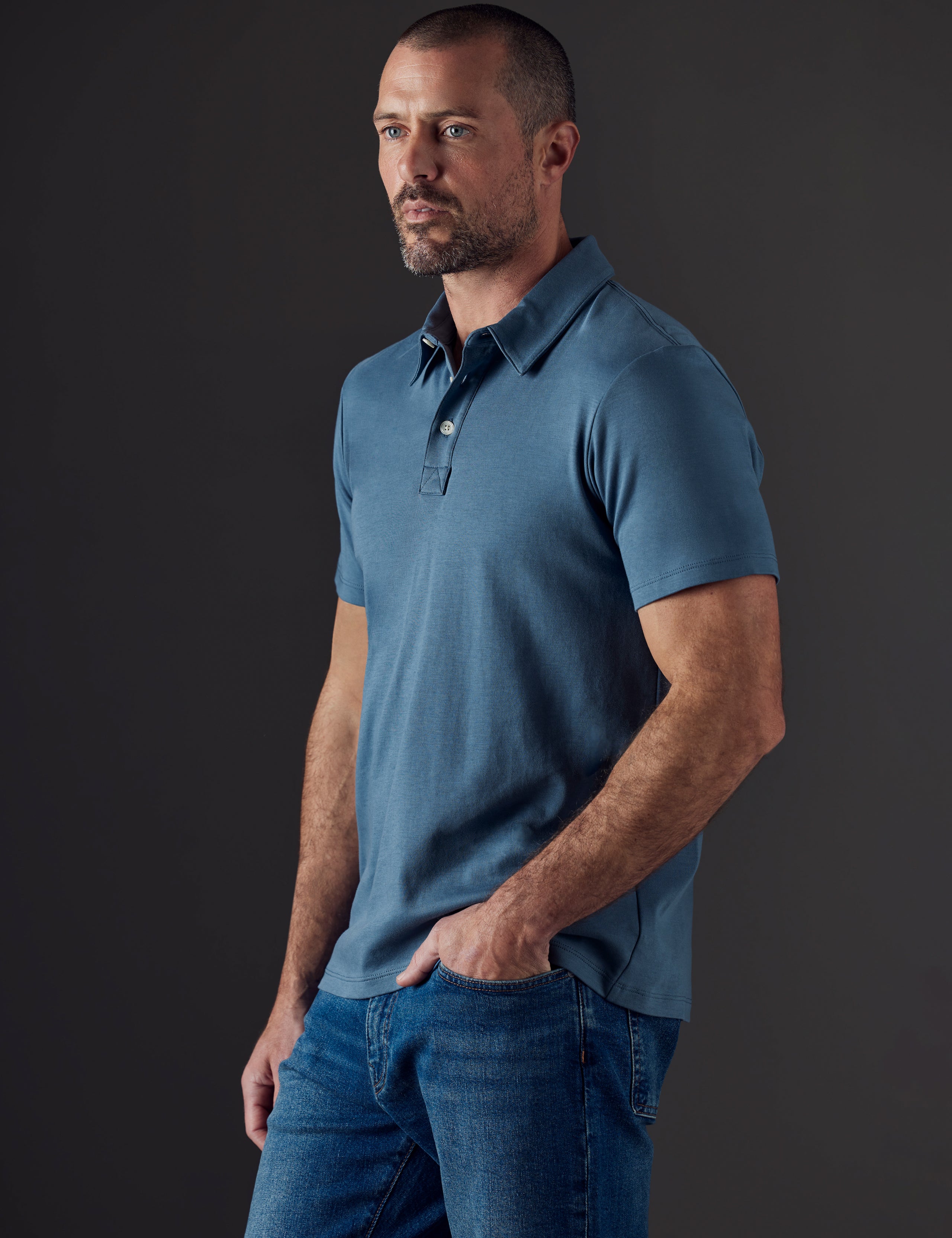 Front 3/4 body view of man wearing Emery Pima Polo in Coastal Blue from AETHER Apparel.