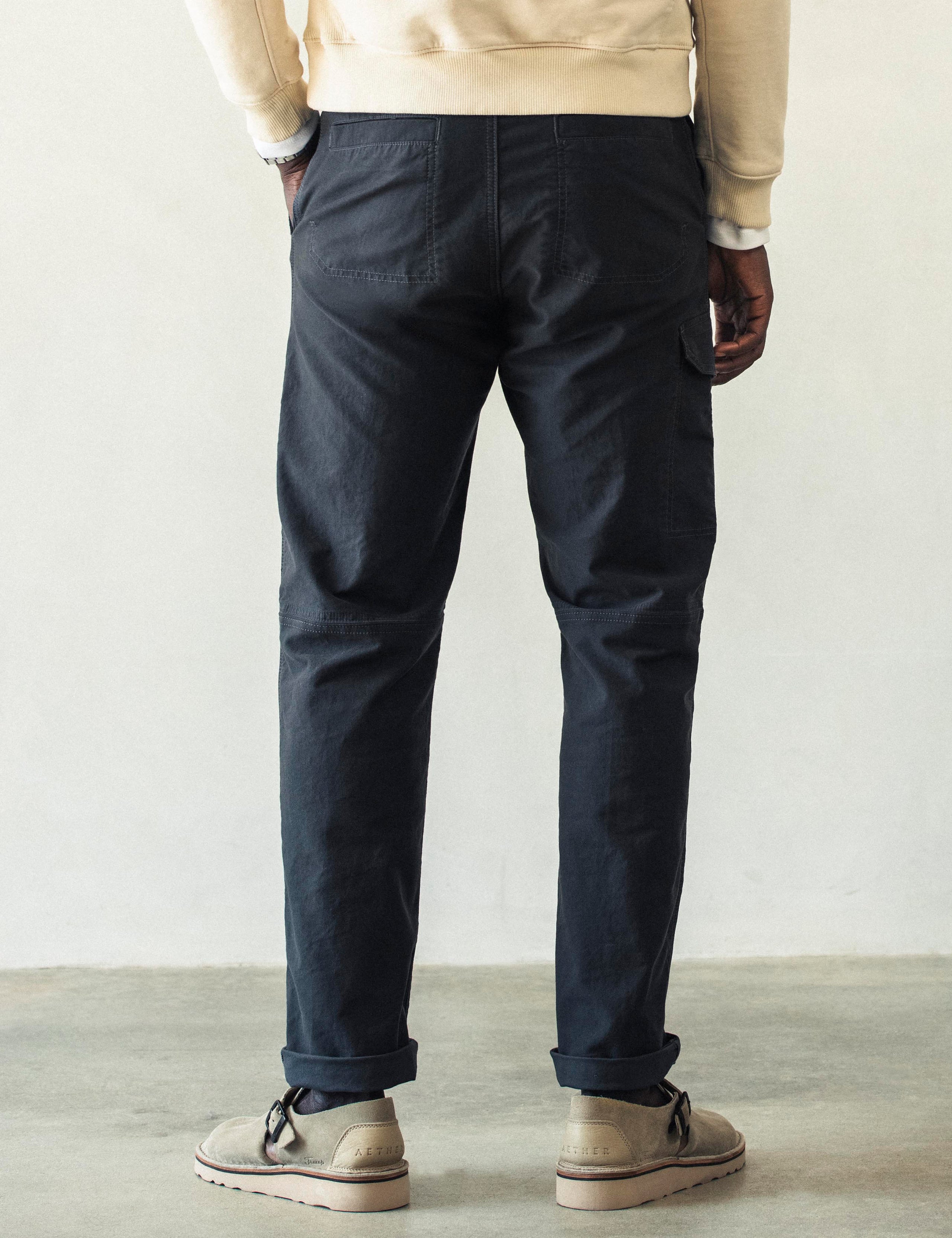 Rear lower body view of man wearing Fairfax Pant 2.0 in Graphite from AETHER Apparel.