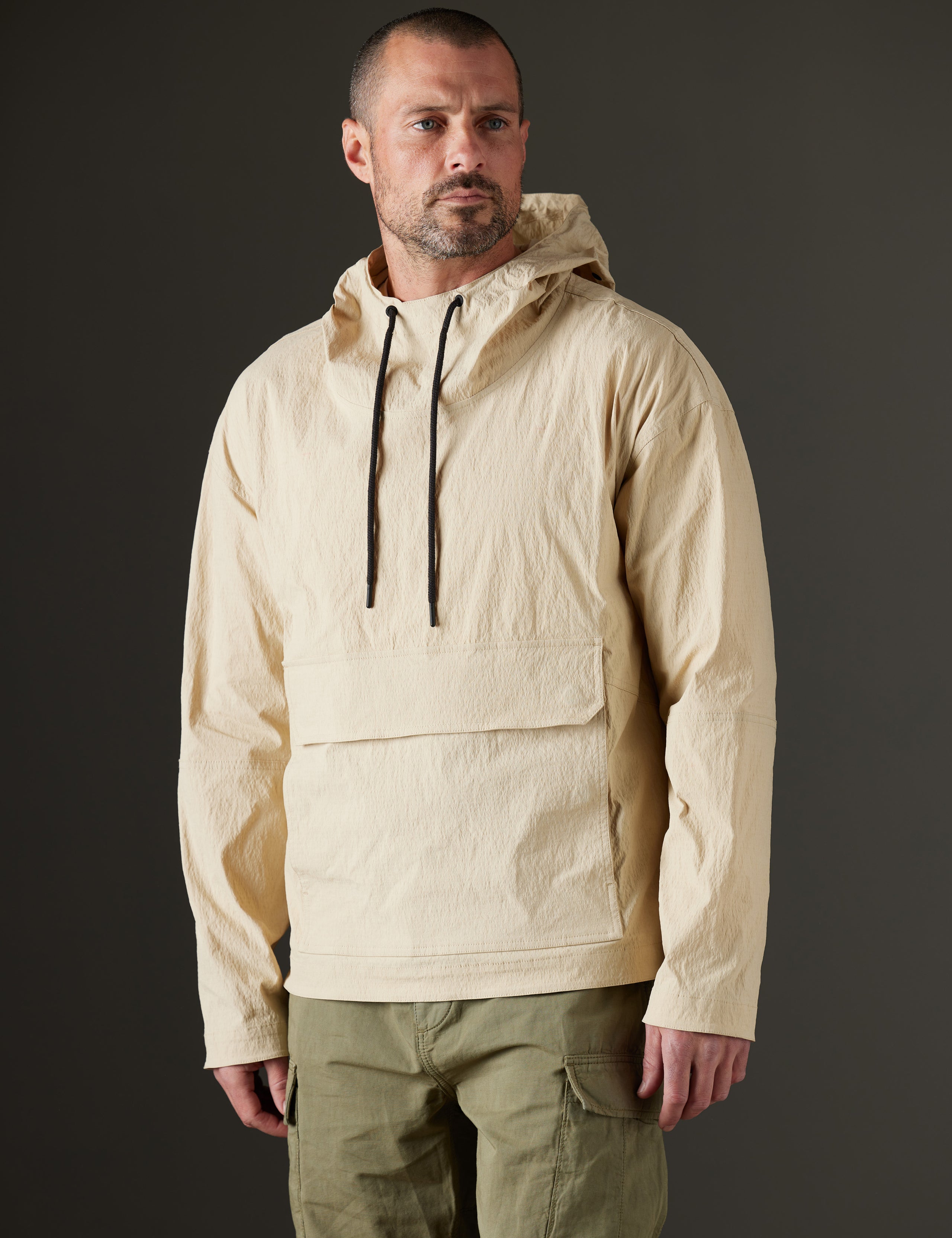 Front 3/4 body view of man wearing Harrier Anorak in Desert Tan from AETHER Apparel.