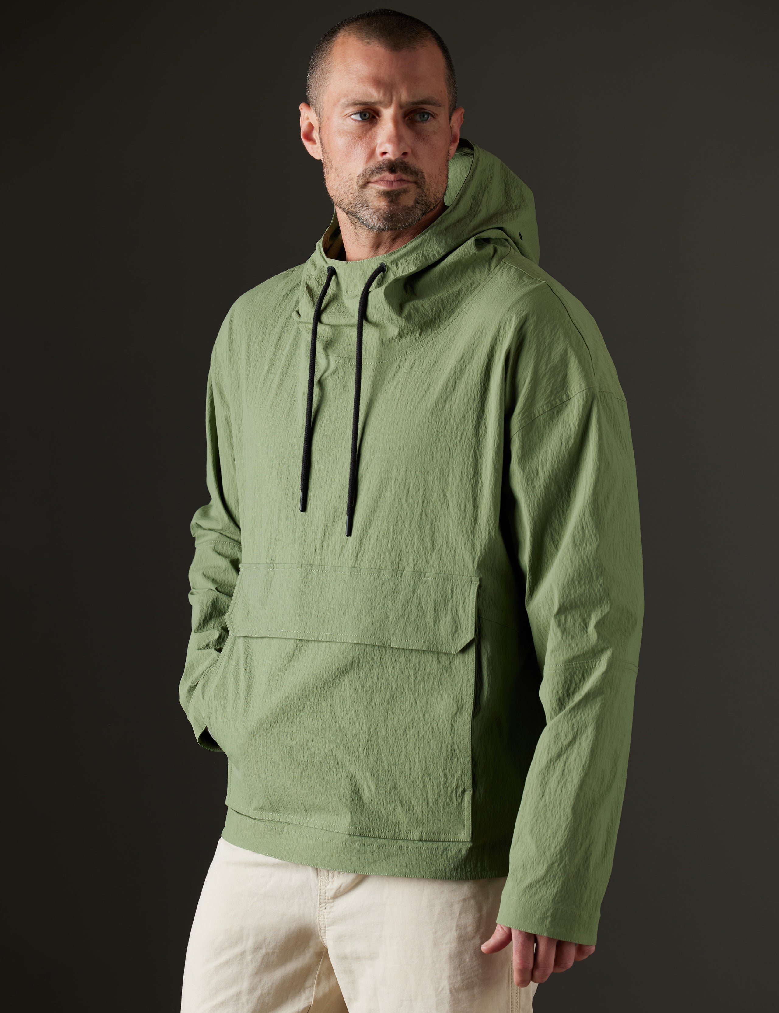 Front 3/4 body view of man wearing Harrier Anorak in Mineral Green from AETHER Apparel.