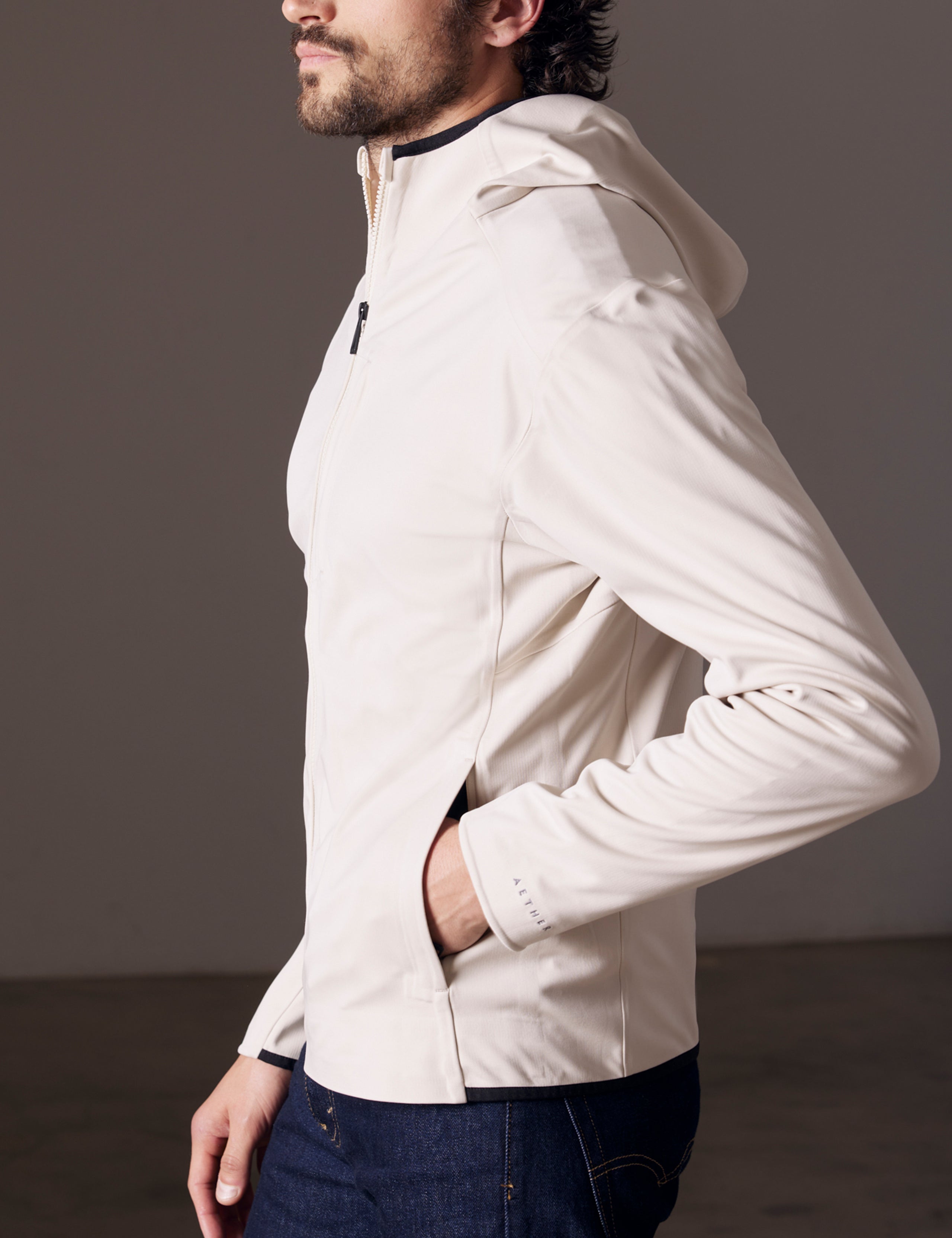 Side profile body view of man wearing Hooded Tech-Fleece Full-Zip in Bone white from AETHER Apparel.