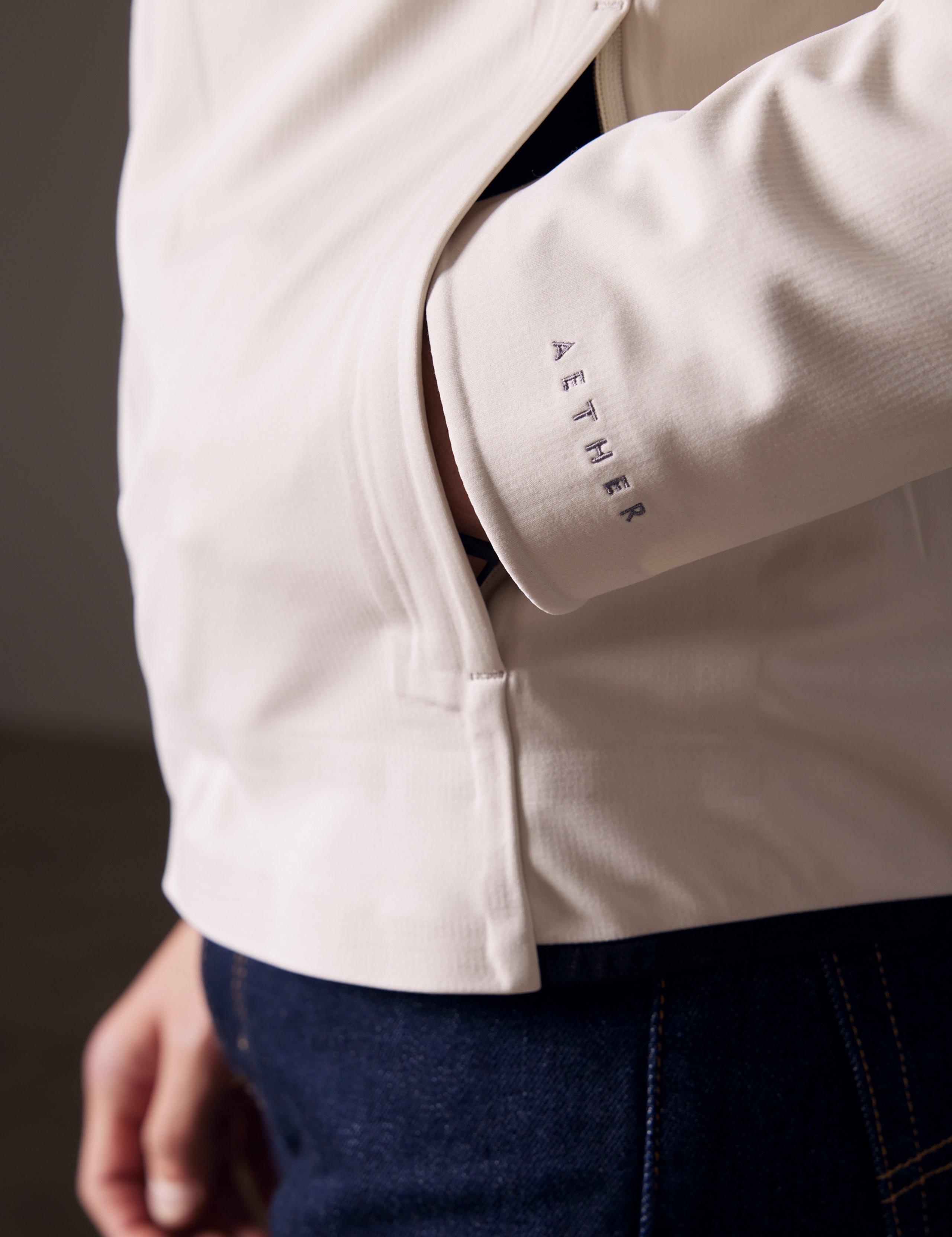 Detailed view of man putting hand in pocket of Hooded Tech-Fleece Full-Zip in Bone white from AETHER Apparel.