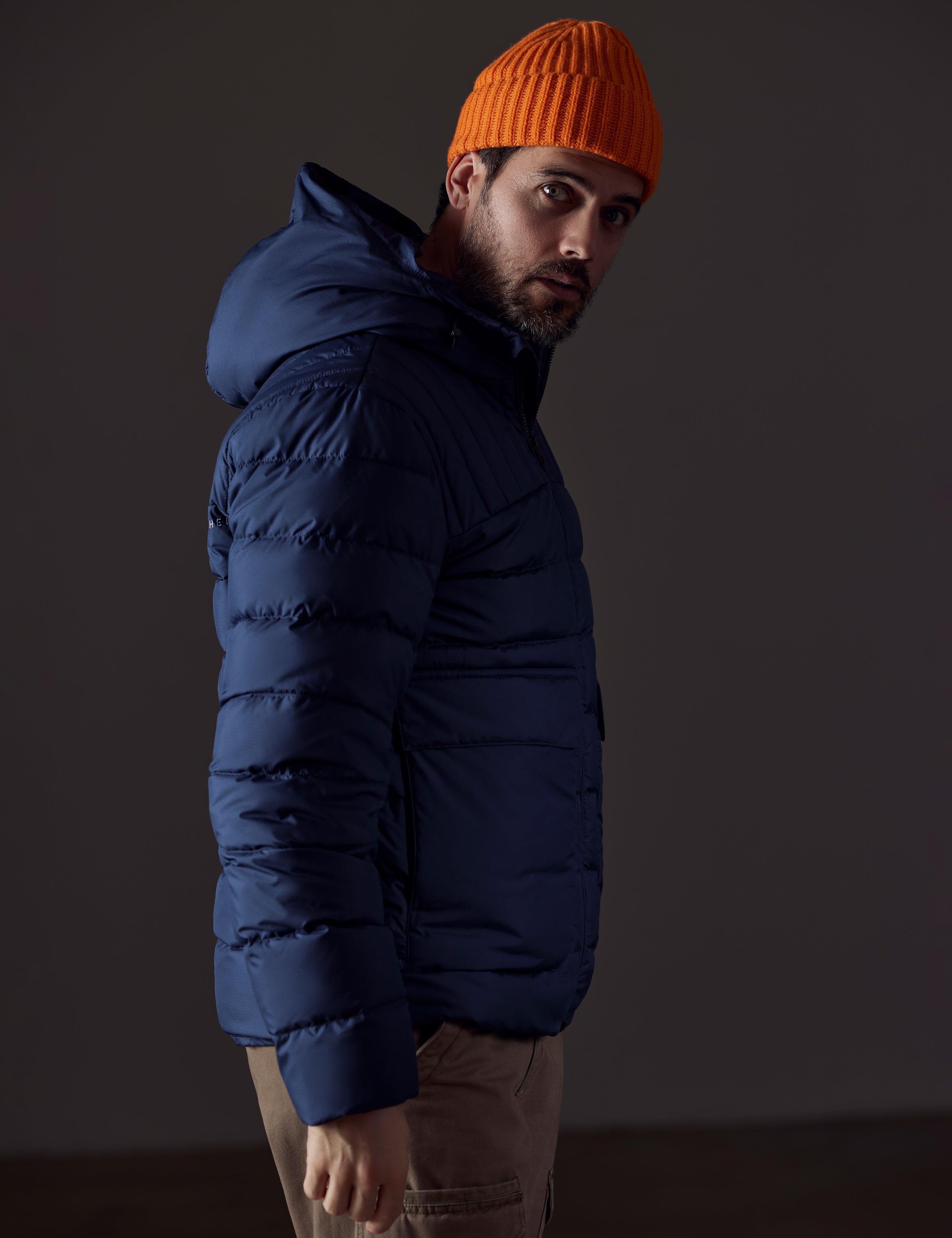 Side profile body view of man wearing Hudson Down Jacket in Total Eclipse dark blue from AETHER Apparel.