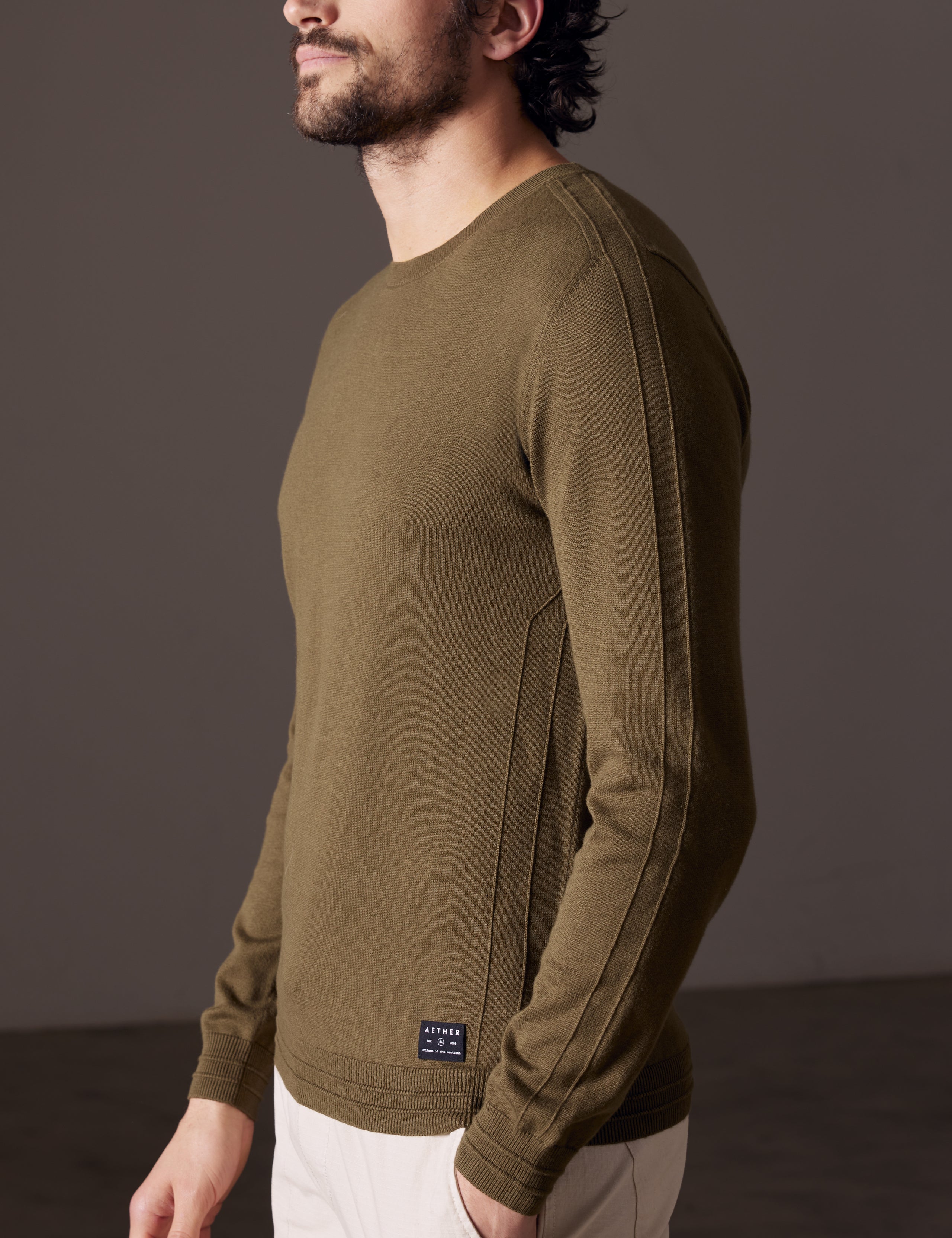 Side profile view of man wearing Irving Sweater in Command Green from AETHER Apparel.