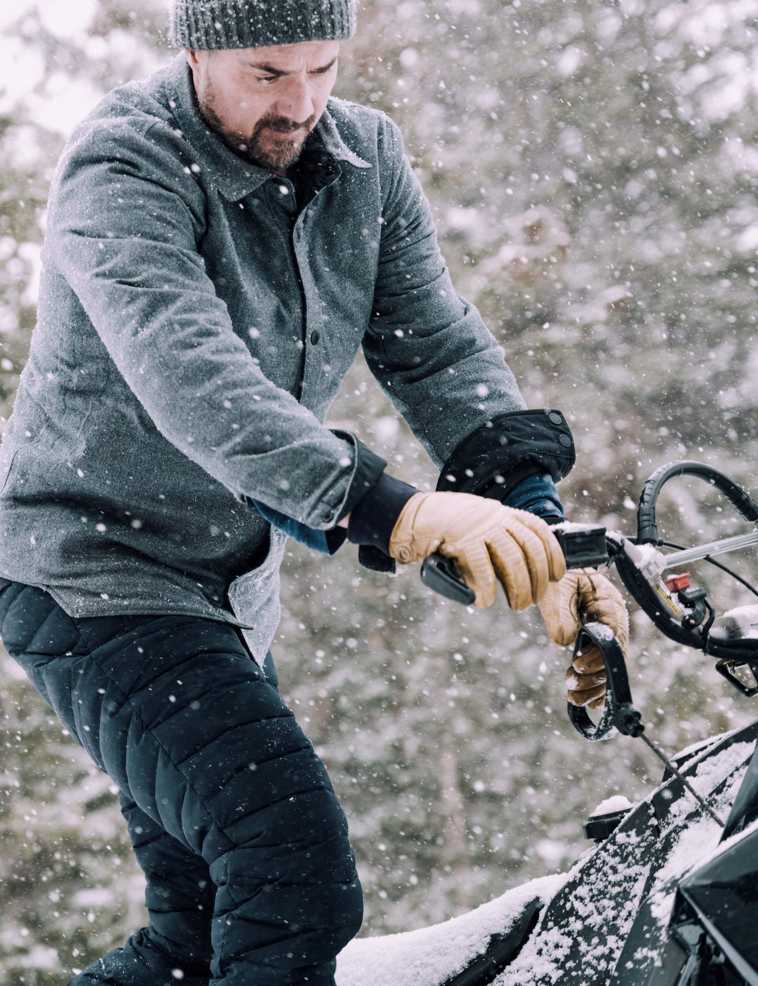 Outdoor lifestyle image of man on snowmobile wearing Launch Pant in Onyx Black from AETHER Apparel. 