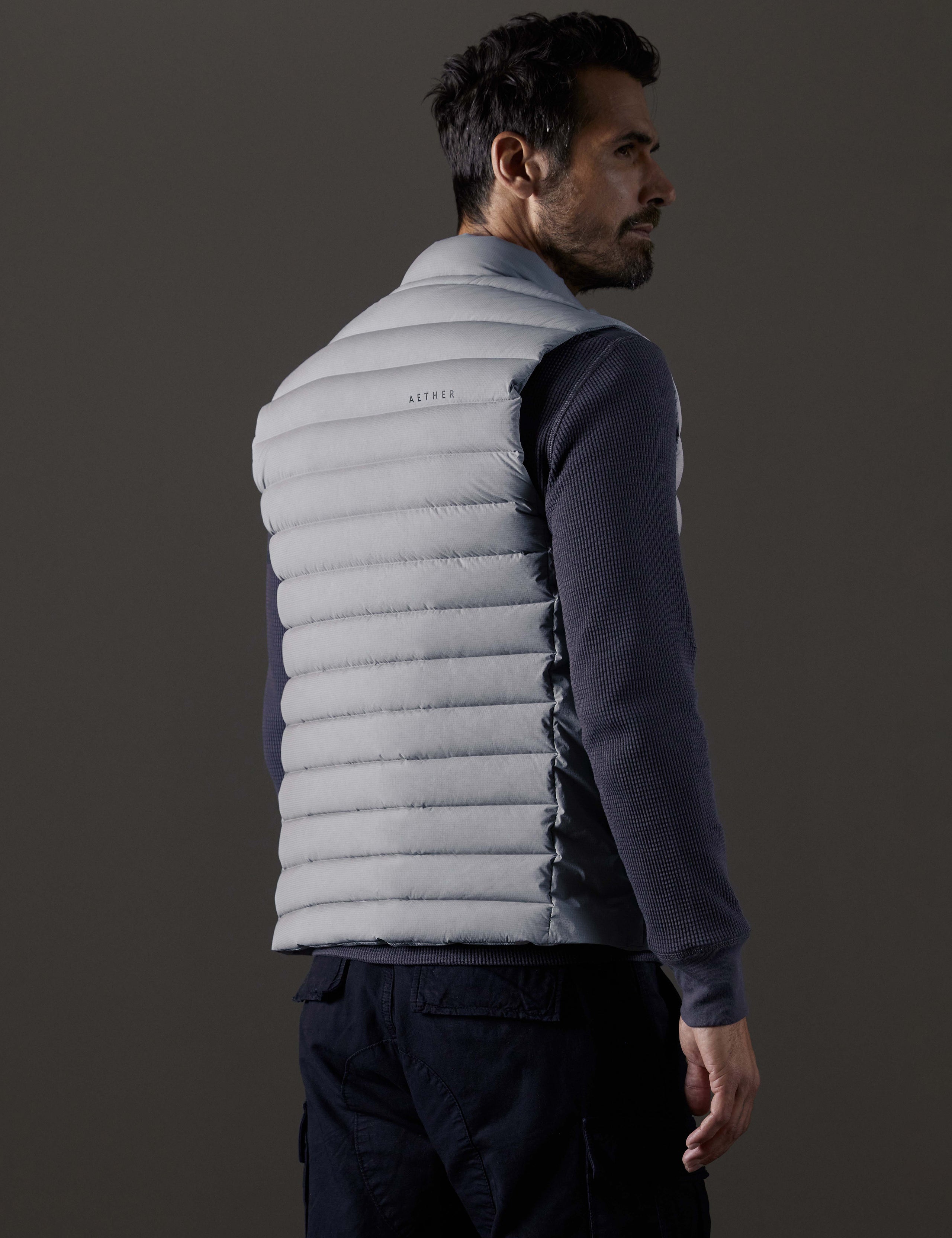 Rear 3/4 body view of man wearing Launch Vest in Sky Grey from AETHER Apparel.