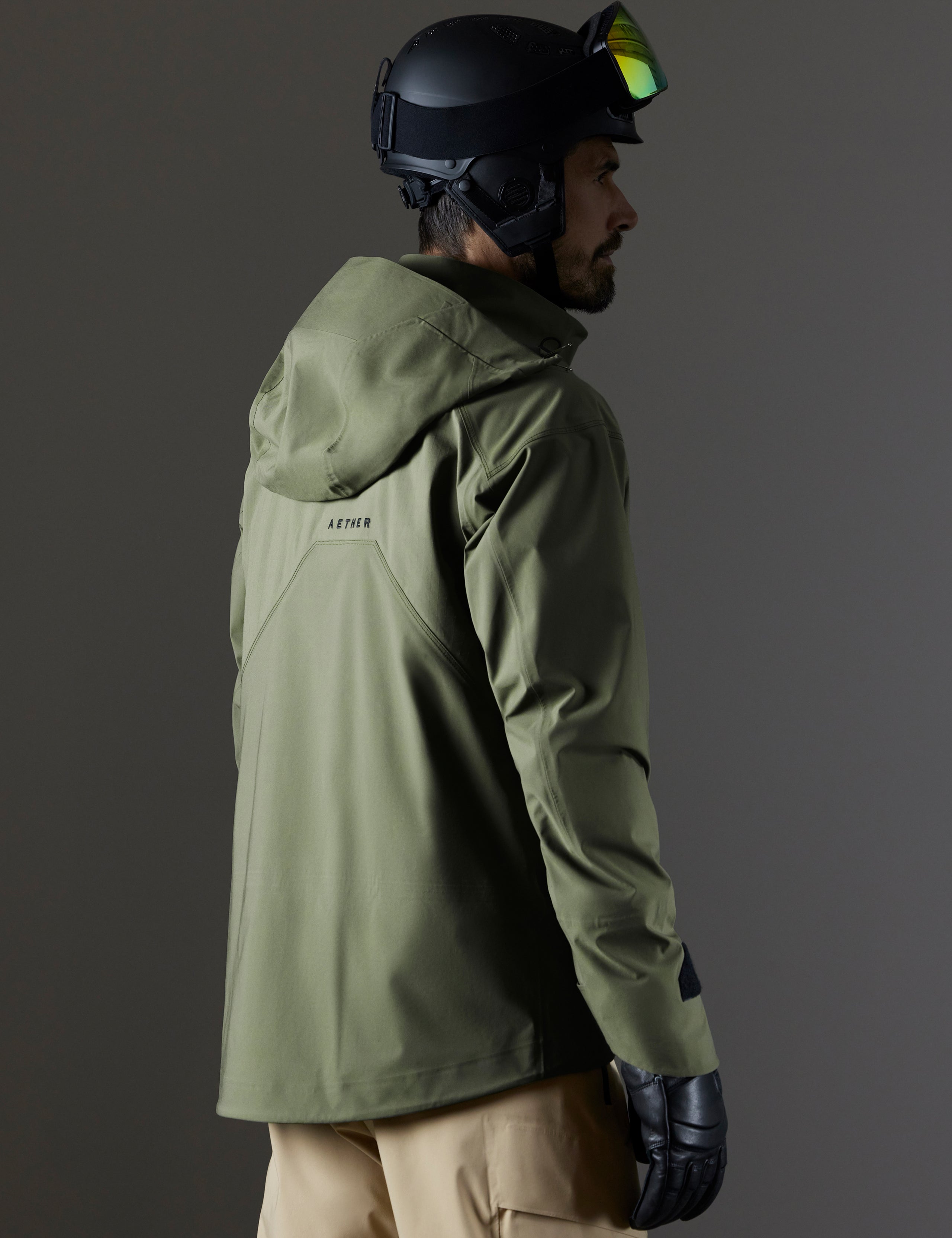 Rear 3/4 body view of man wearing Maverick Snow-Shell Jacket in Fern Green from AETHER Apparel.