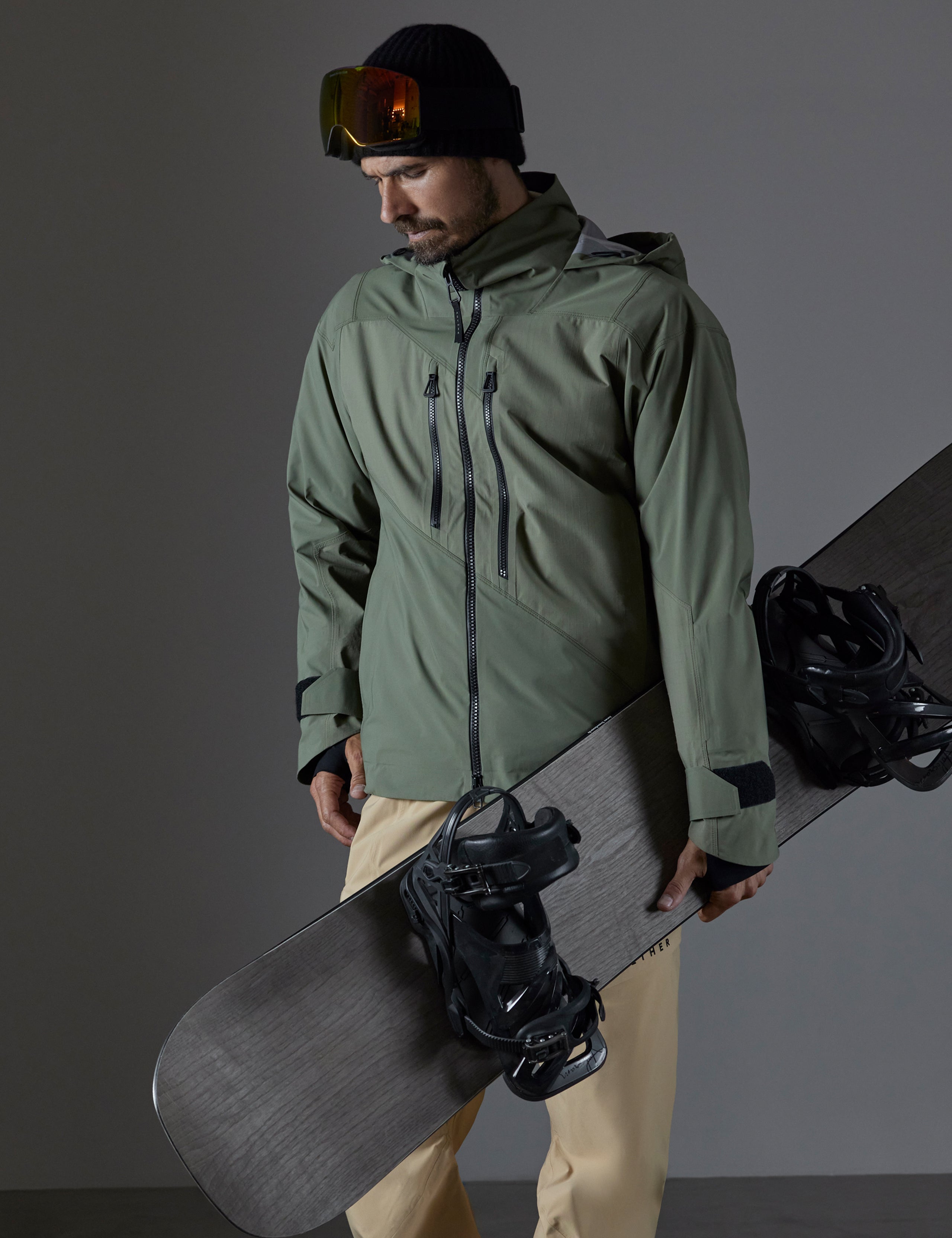 Front body view of man holding snowboard wearing Maverick Snow-Shell Jacket in Fern Green from AETHER Apparel.