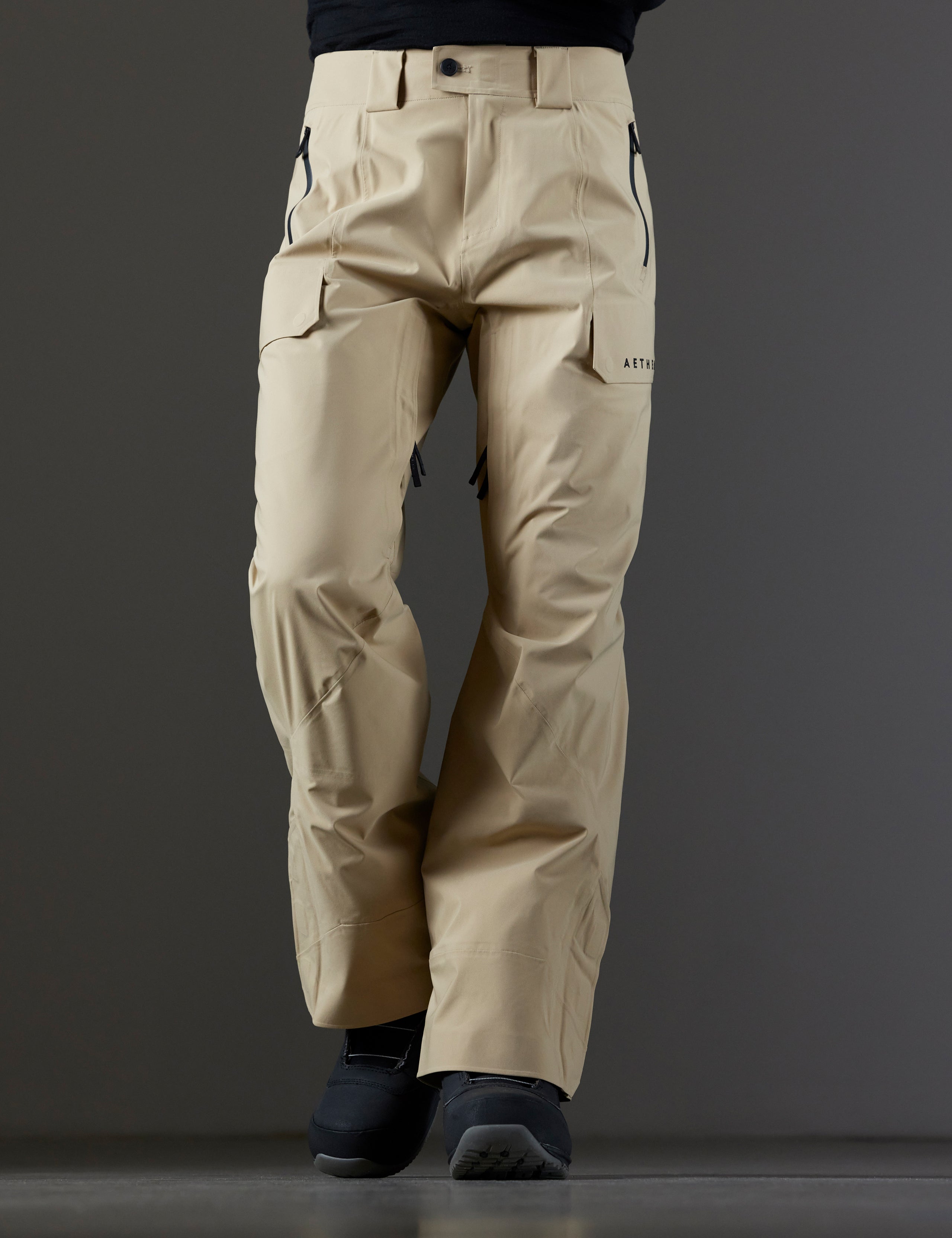Front lower body view of man wearing Maverick Snow-Shell Pant in Desert Tan from AETHER Apparel.