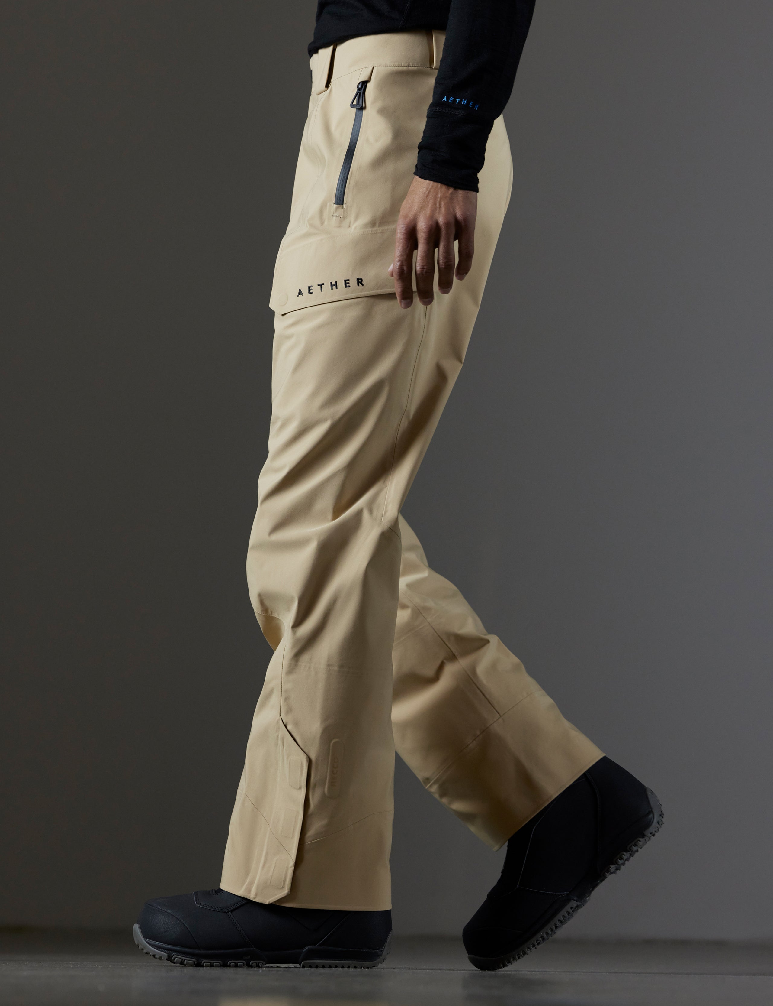 Side profile lower body view of man wearing Maverick Snow-Shell Pant in Desert Tan from AETHER Apparel.