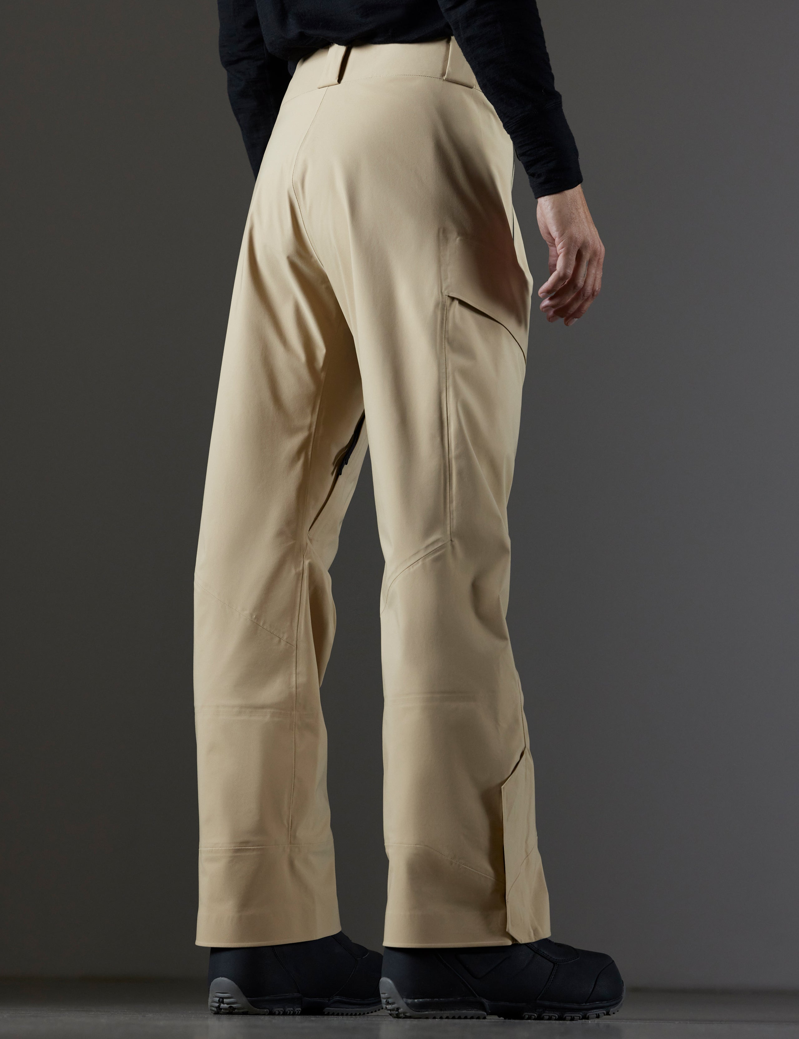 Rear 3/4 lower body view of man wearing Maverick Snow-Shell Pant in Desert Tan from AETHER Apparel.