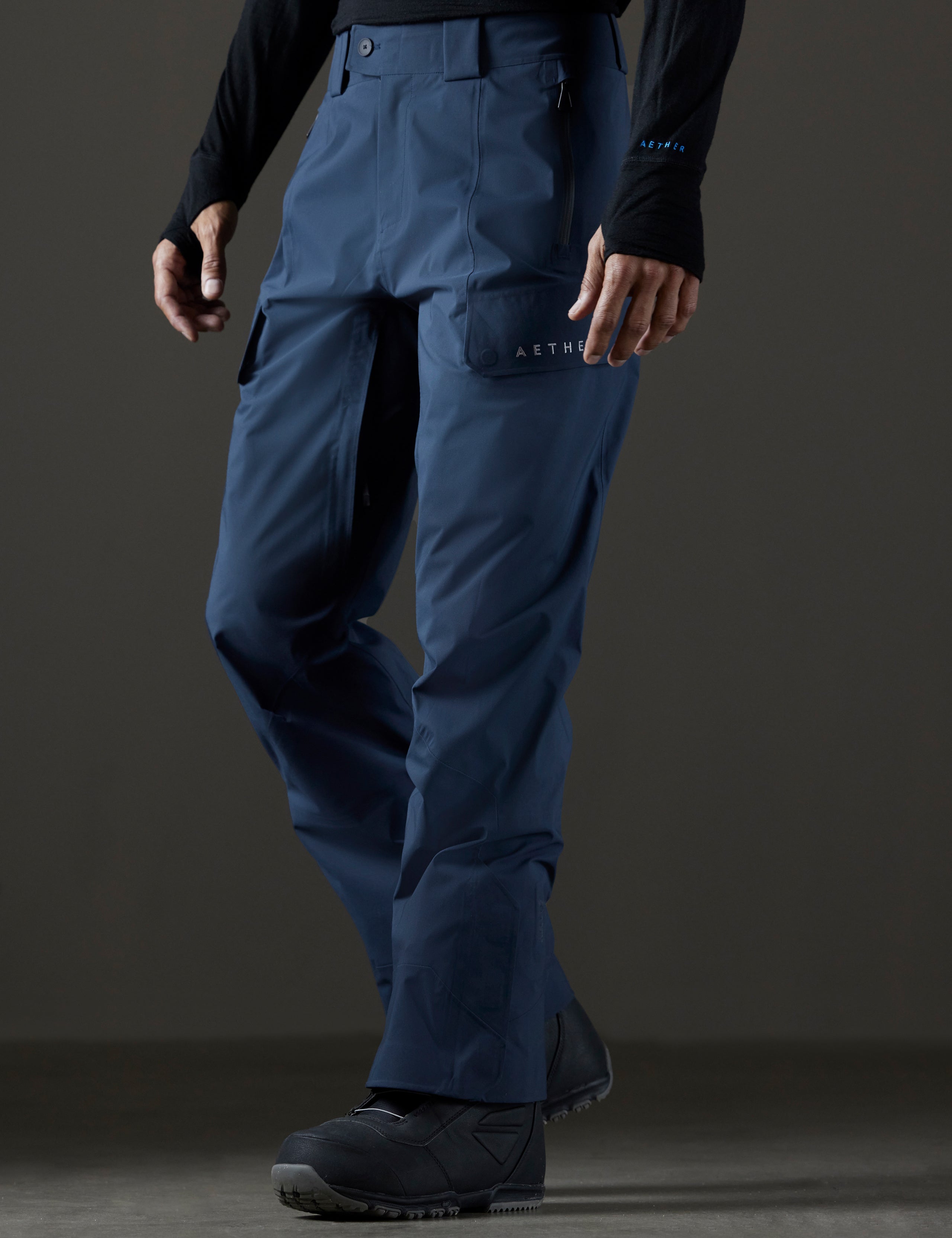 Front 3/4 lower body view of man wearing Maverick Snow-Shell Pant in Total Eclipse dark blue from AETHER Apparel.