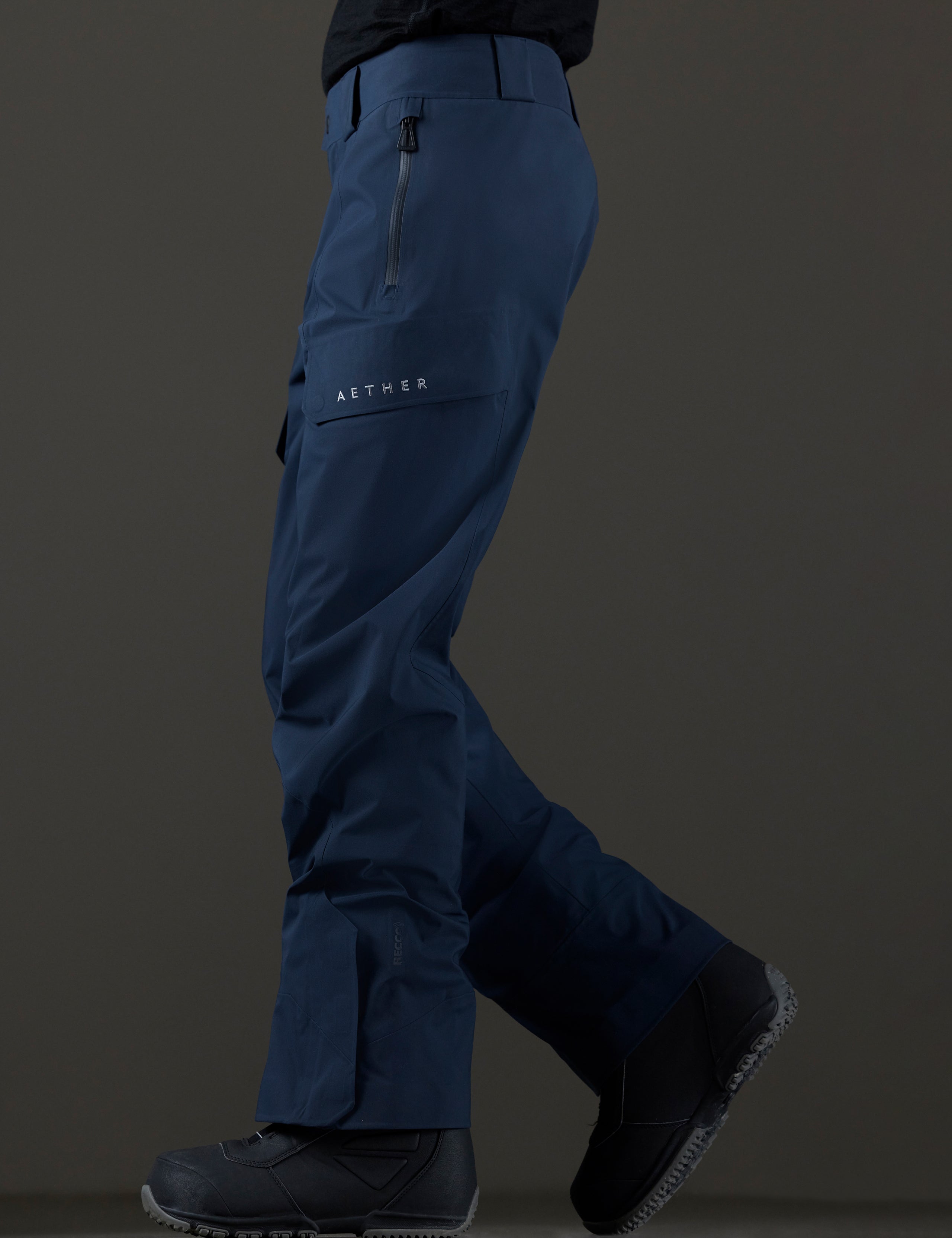Side profile lower body view of man wearing Maverick Snow-Shell Pant in Total Eclipse dark blue from AETHER Apparel.